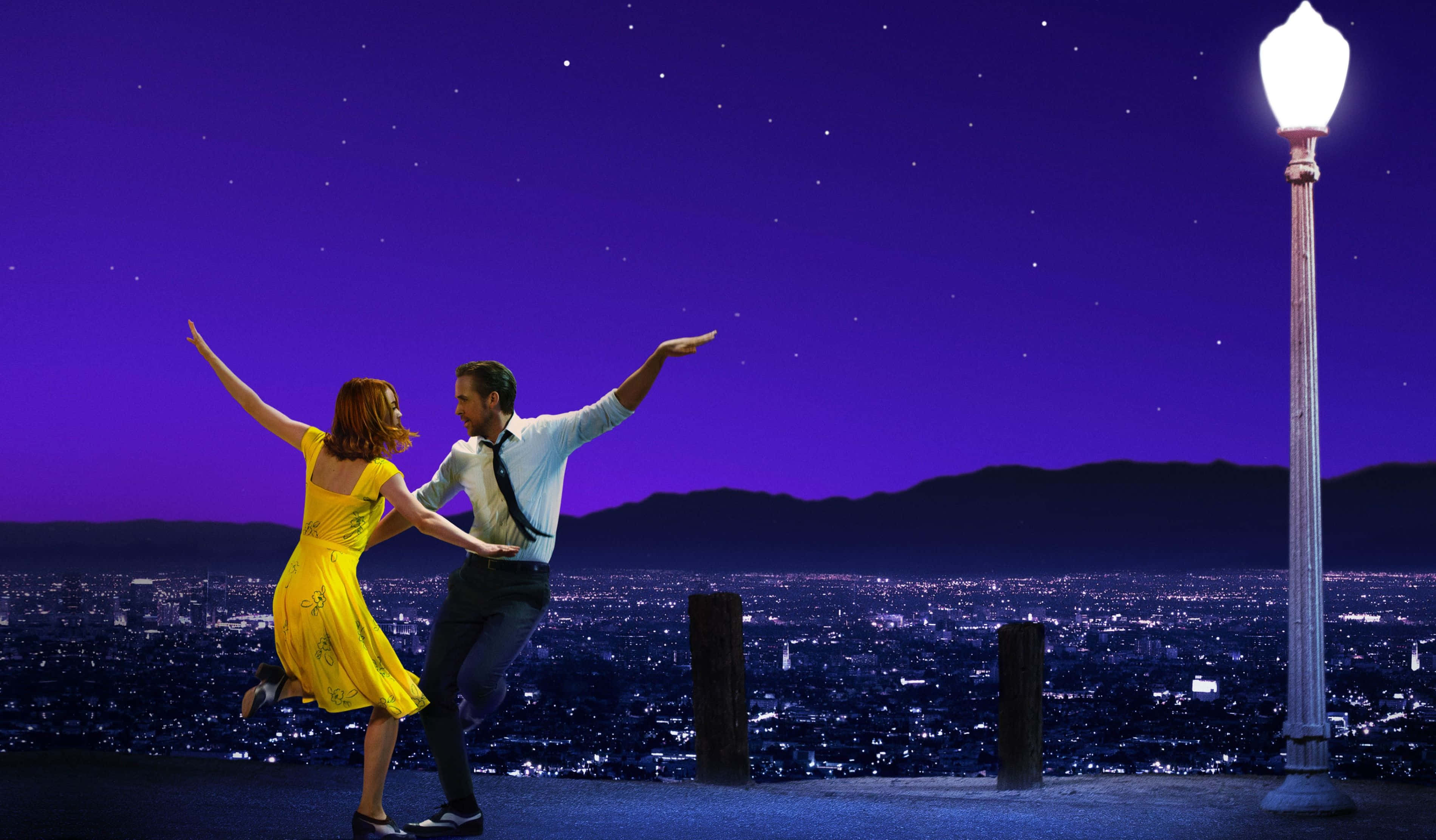 La La Land 4K 桌布 壁紙 — 一對情侶在夜晚的屋頂上快樂地跳舞，背景是發光的街燈和廣闊的城市景觀，上方是繁星點點的紫色天空。