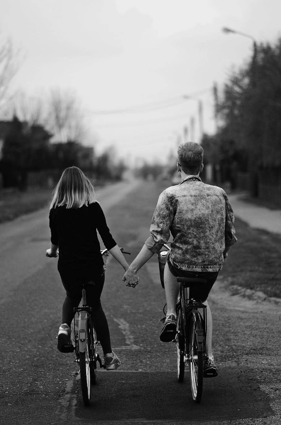 Couples 桌布 壁紙 — 一對情侶在寧靜的住宅街道上騎腳踏車時牽手的黑白照片。