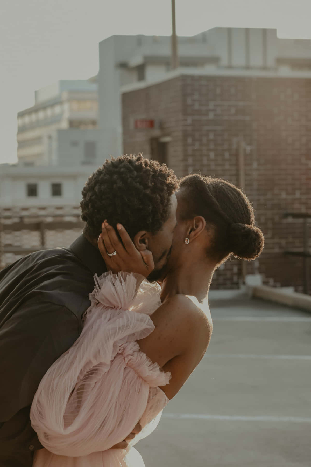 Kissing 桌布 壁紙 — 一對情侶在屋頂上親吻，金色時光的光芒沐浴著他們在都市建築物前的擁抱。