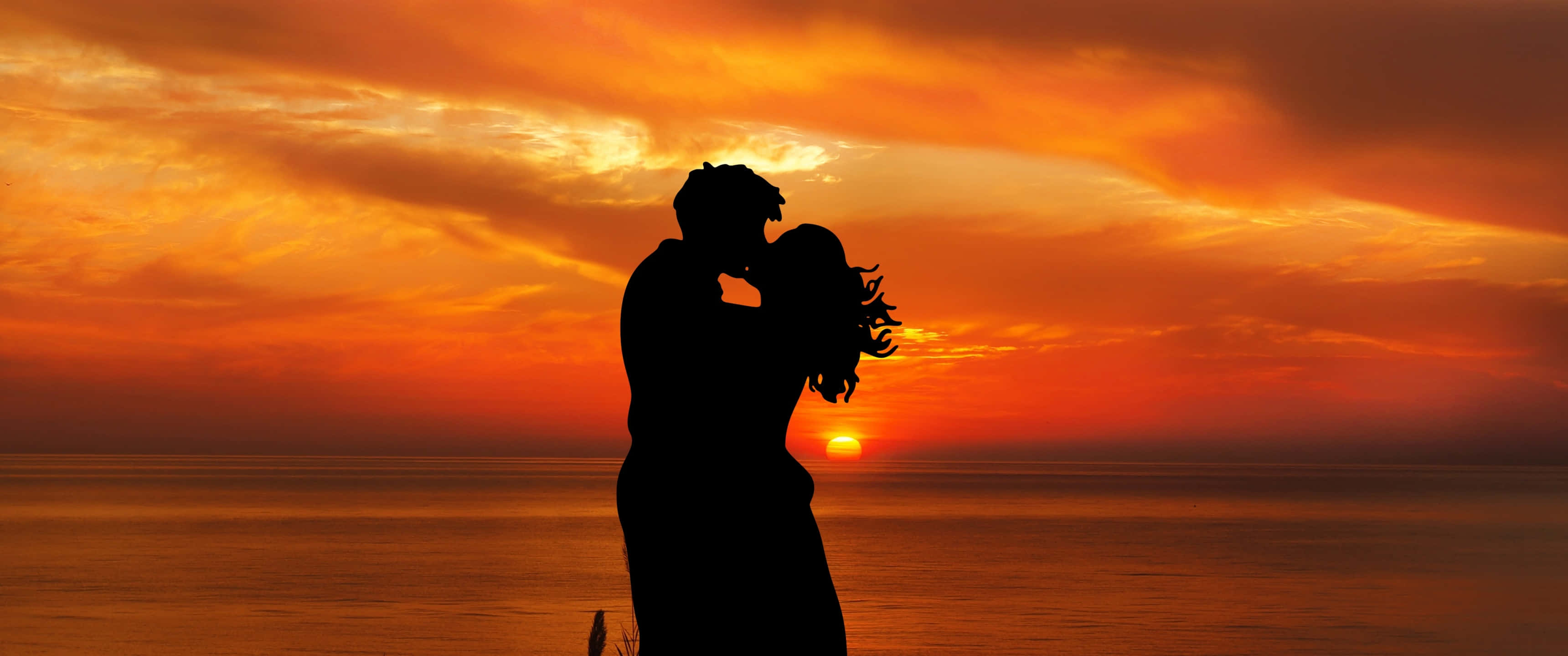 Silhouette 桌布 壁紙 — 一對情侶在平靜的海平線上日落時分接吻的浪漫剪影。