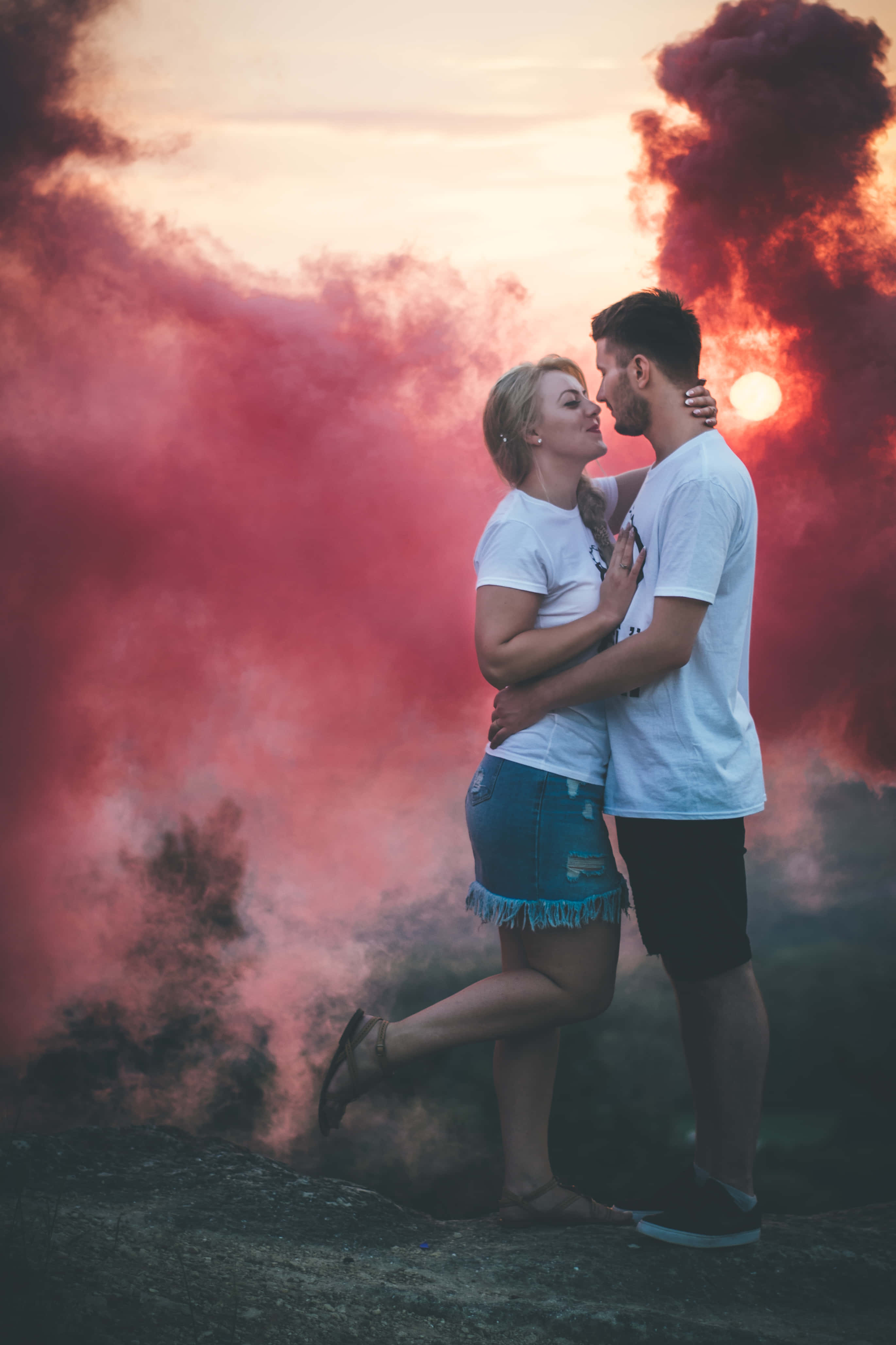 Lovers 桌布 壁紙 — 一對情侶在日落時分，以戲劇性的紅色煙霧為背景，溫柔地擁抱。