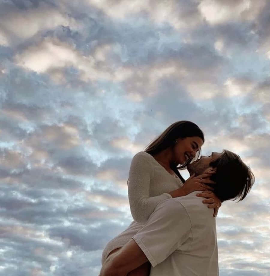 Boyfriend And Girlfriend 桌布 壁紙 — 一對情侶在日落時分戲劇性的多雲天空下分享歡樂的擁抱。