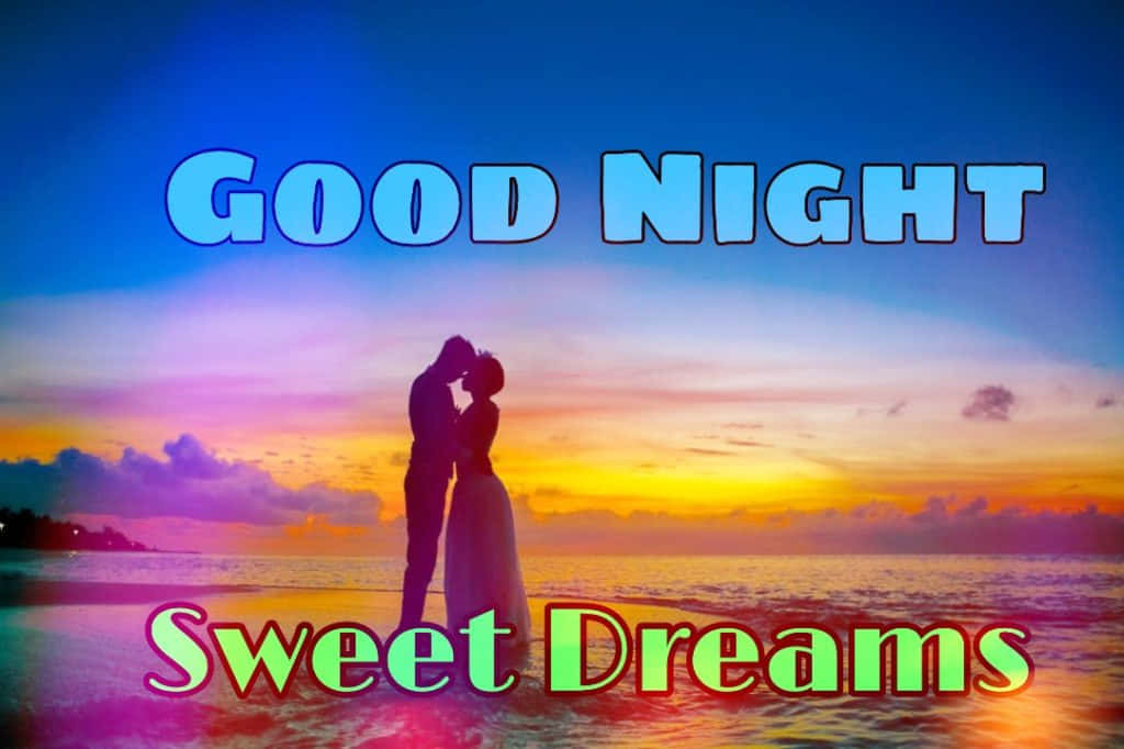 Goodnight Kiss 桌布 壁紙 — 一對情侶在日落時分於沙灘上接吻的浪漫剪影，天空色彩繽紛，並帶有「Good Night Sweet Dreams」文字。