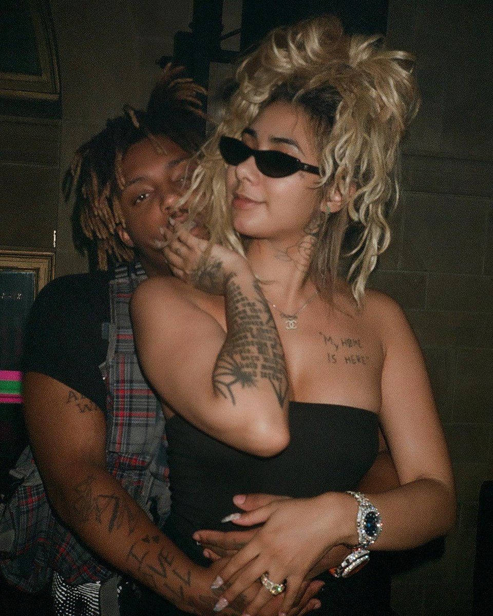 Juice Wrld And Ally 桌布 壁紙 — 一對情侶在昏暗的房間中親密擁抱，刺青和太陽眼鏡增添了前衛風格。