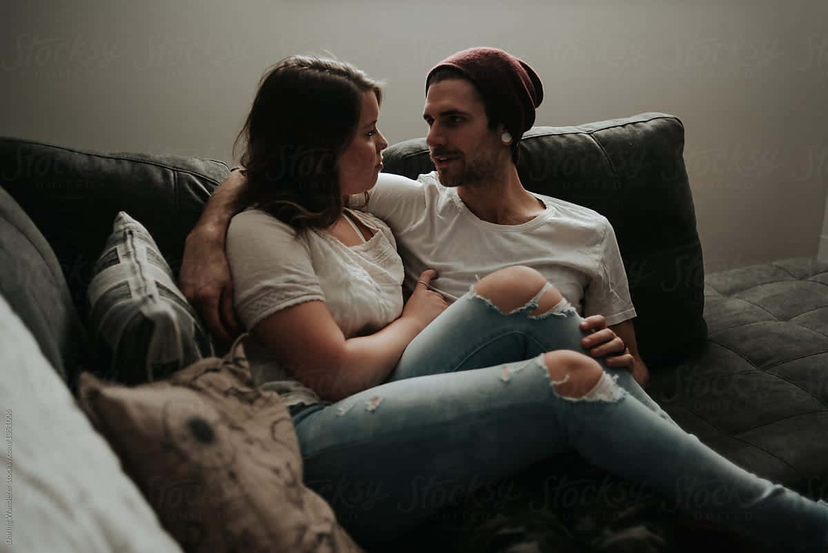 couple love 桌布 壁紙 — 一對情侶在昏暗的沙發上分享親密時刻，房間光線柔和，色調柔和，枕頭舒適。