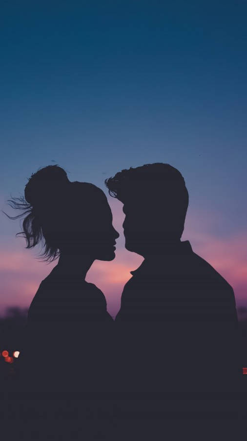 Love Cute Couple 桌布 壁紙 — 一對情侶在暮色天空下相對而立的剪影，帶有柔和粉紅與藍色調。