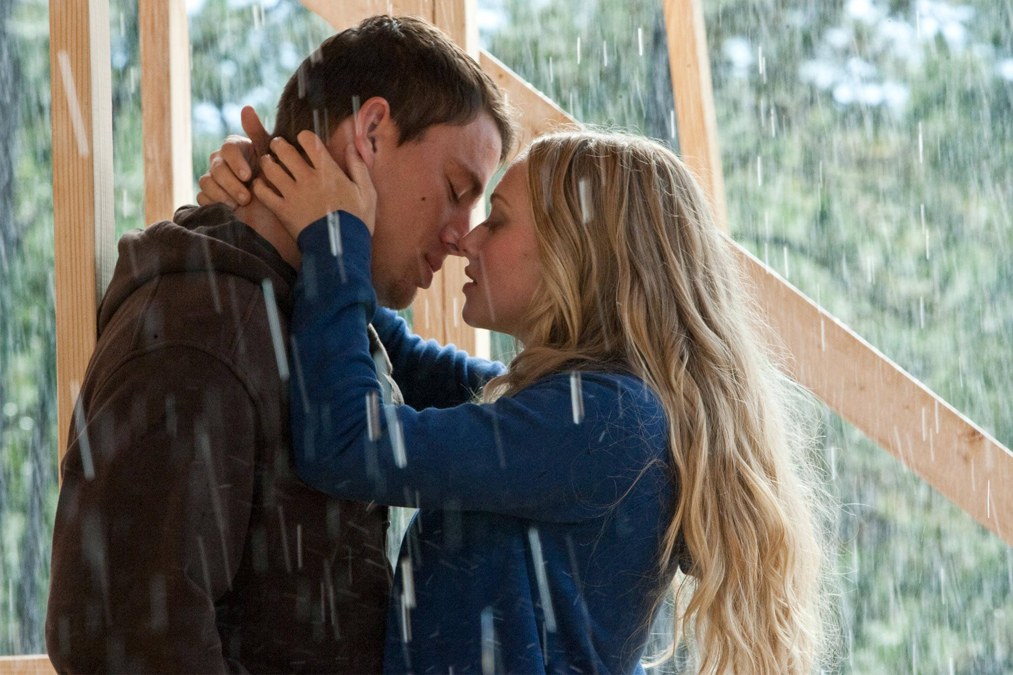 Amanda Seyfried 桌布 壁紙 — 一對情侶在木結構內親吻，雨水順著身後的玻璃窗流下。