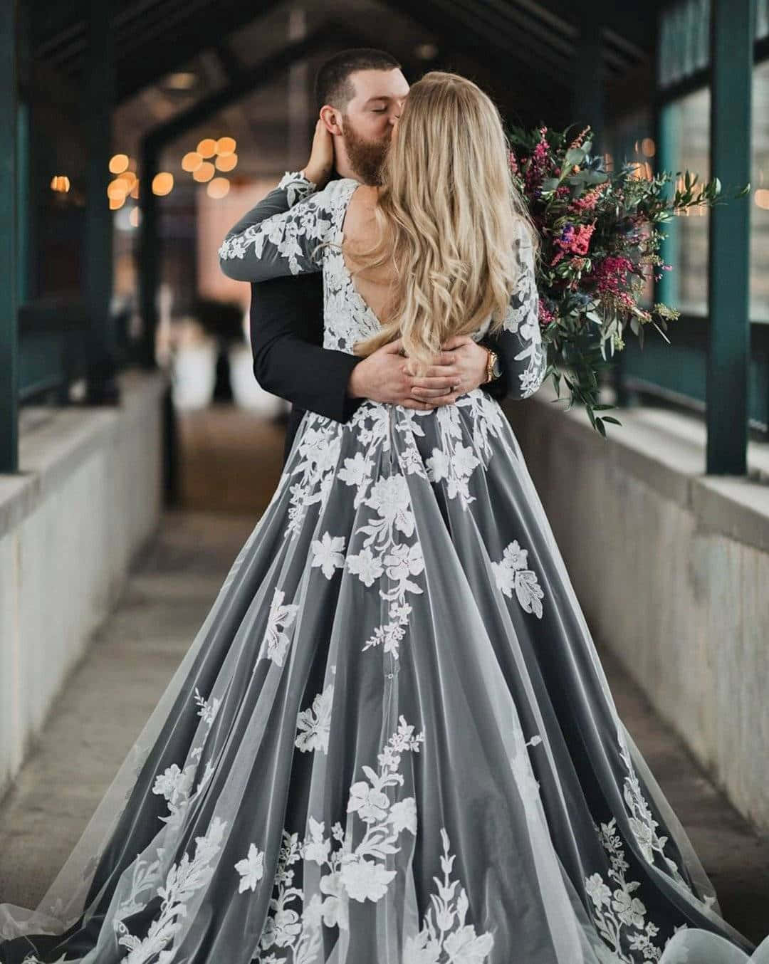 Black And White Wedding 桌布 壁紙 — 一對情侶在溫暖的散景燈光下親吻，新娘手持鮮豔的花束。