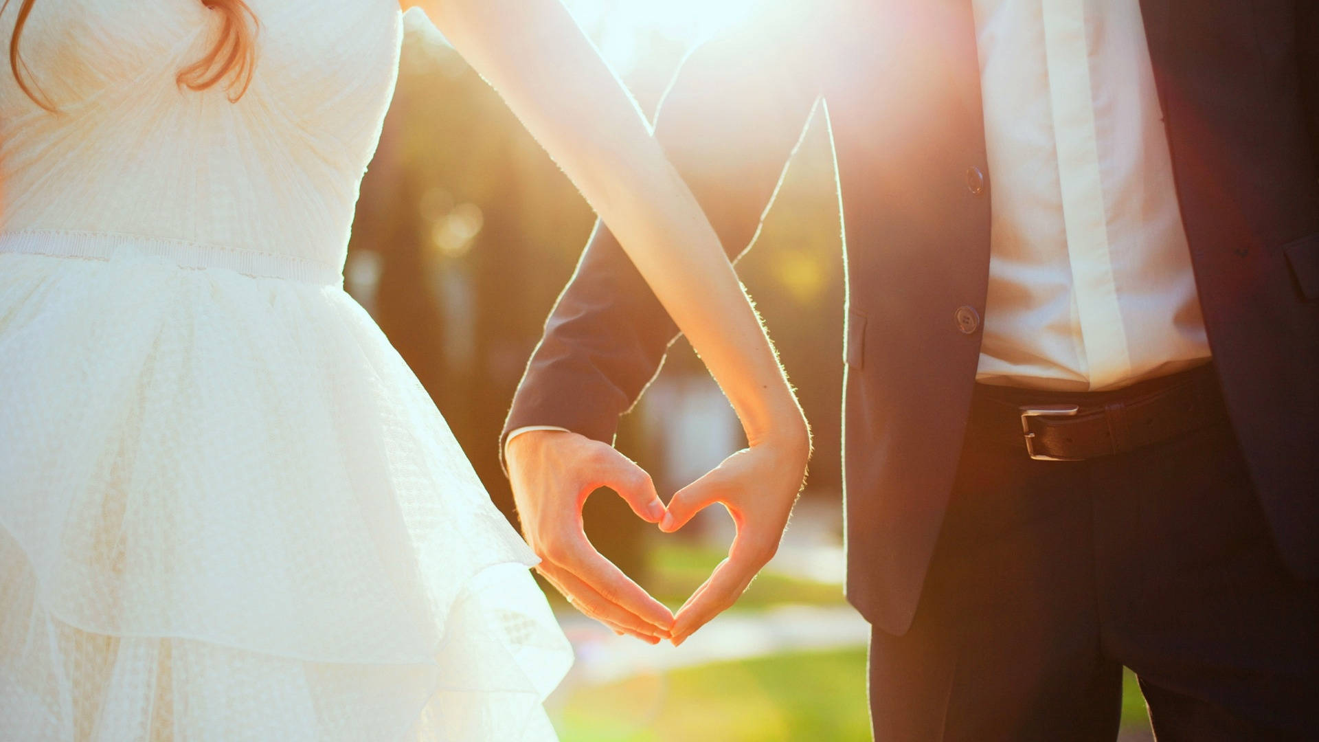 Wedding 桌布 壁紙 — 一對情侶在溫暖的金色夕陽下用手形成心形。