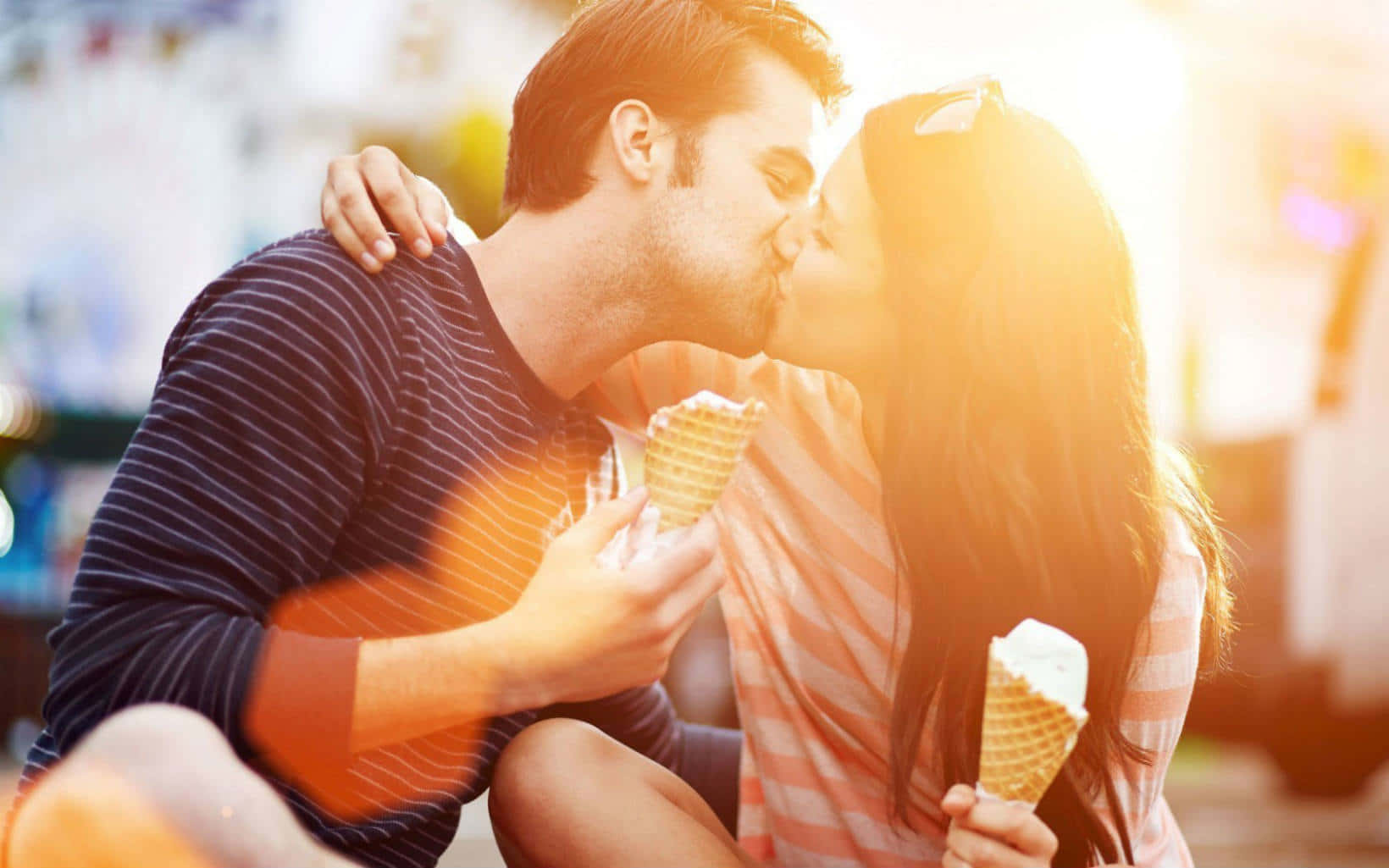 Kissing 桌布 壁紙 — 一對情侶在溫暖的金色陽光下，手持冰淇淋甜筒甜蜜接吻。