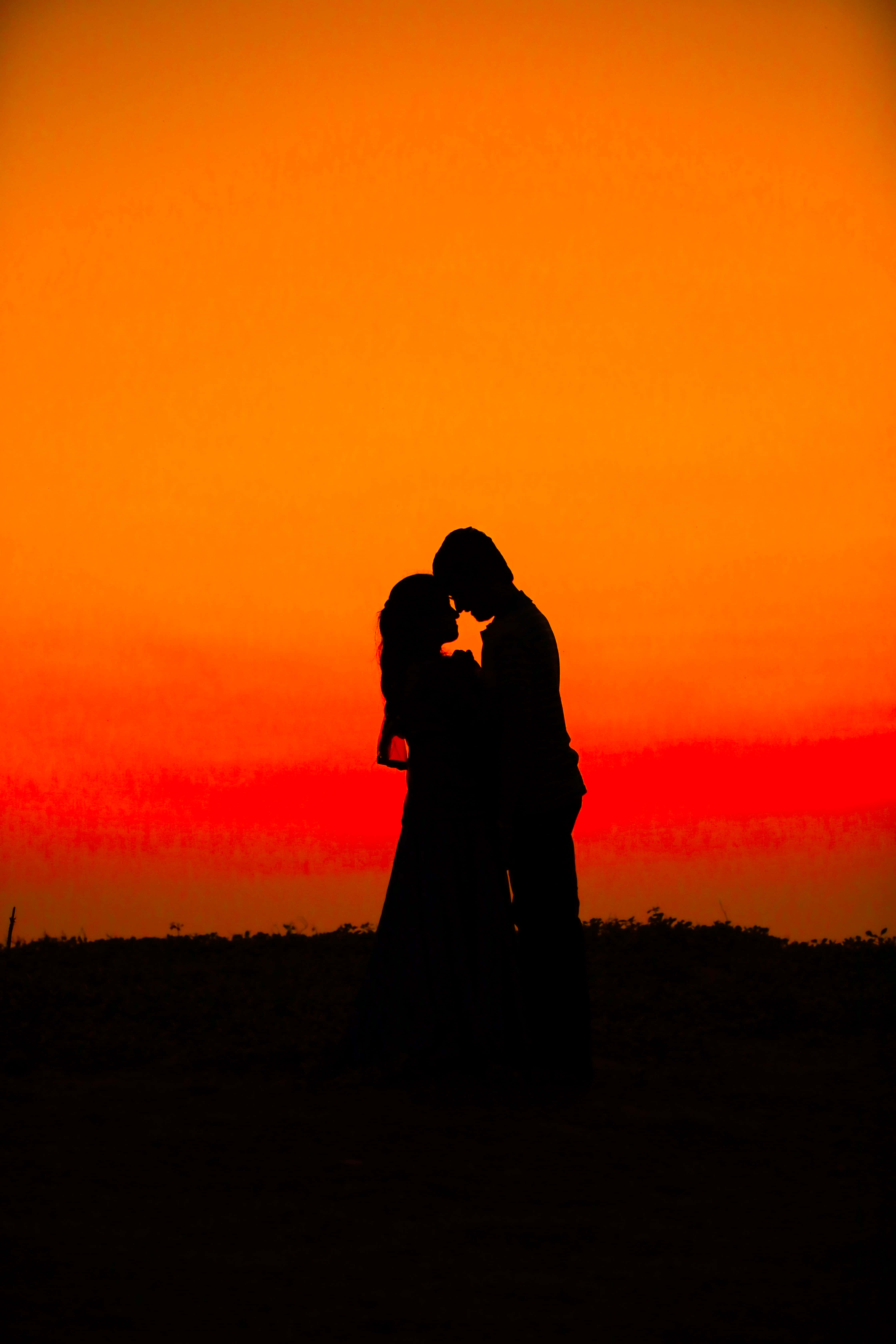 Lovers 桌布 壁紙 — 一對情侶在火紅橙色的日落天空下擁抱親吻的浪漫剪影。