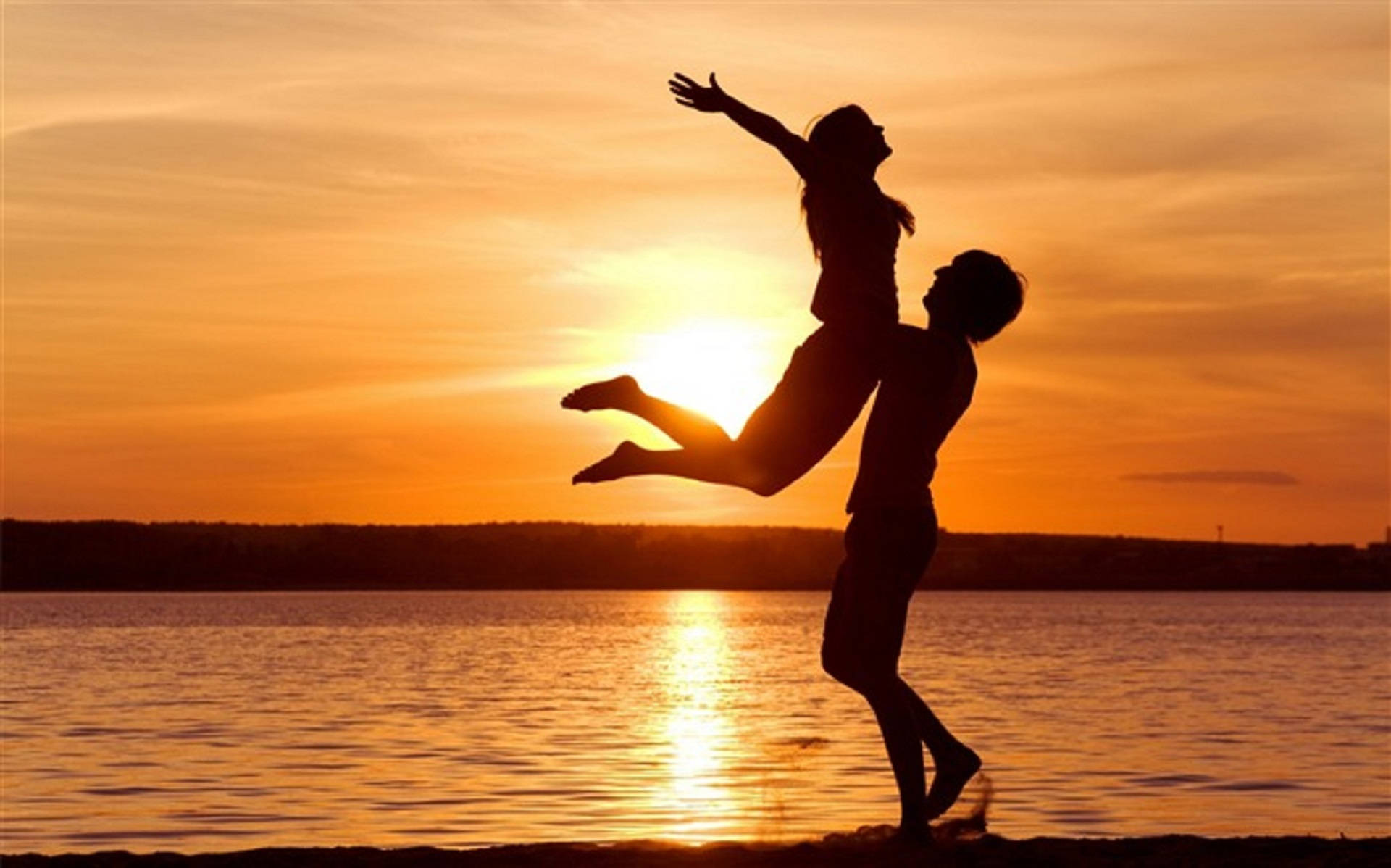 Romantic Love 桌布 壁紙 — 一對情侶在火紅的夕陽下剪影，男子將女子歡樂地舉起在水面之上。