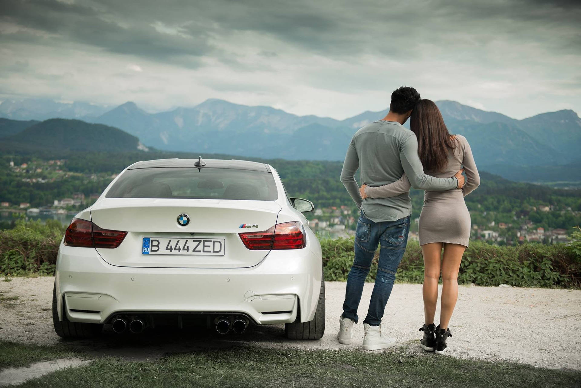 情侶在白色BMW M4附近擁抱，俯瞰群山。