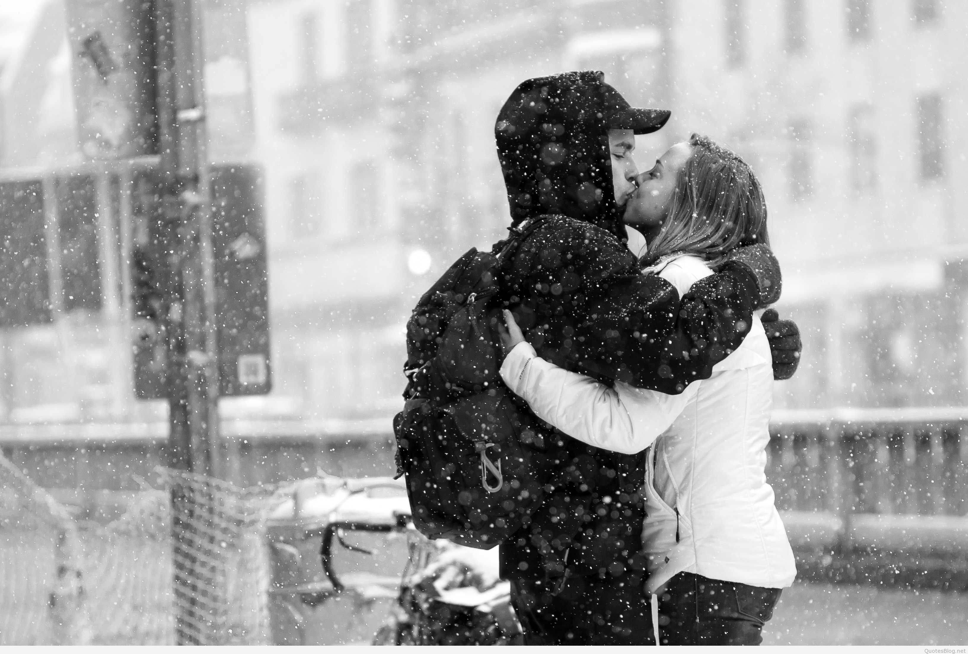 Love Story 桌布 壁紙 — 一對情侶在積雪的都市街道上熱情擁抱親吻，雪花在他們周圍飄落。