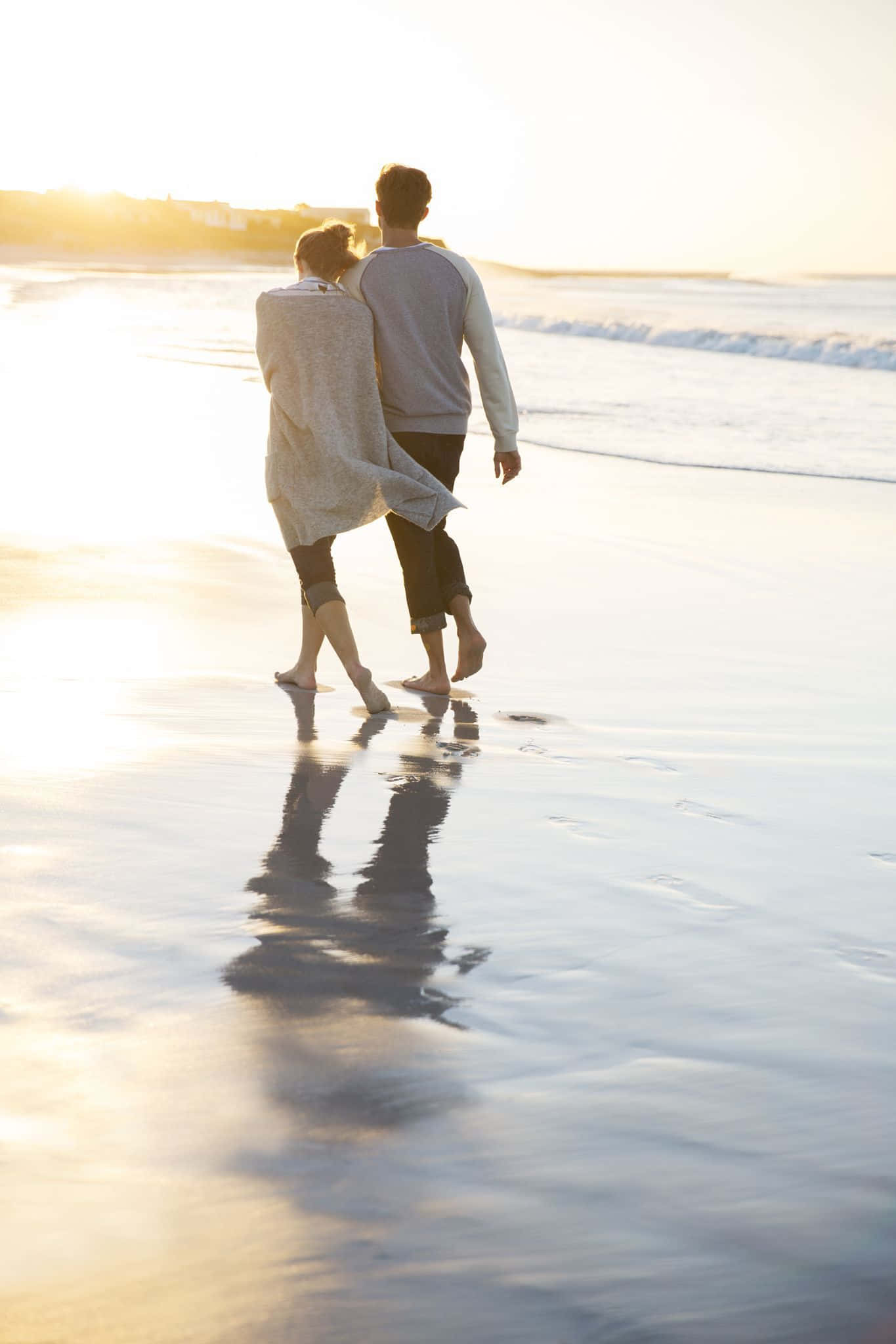 Romance 桌布 壁紙 — 一對情侶在金色日落時赤腳走在濕漉漉的海灘上，他們的倒影在水中閃爍。