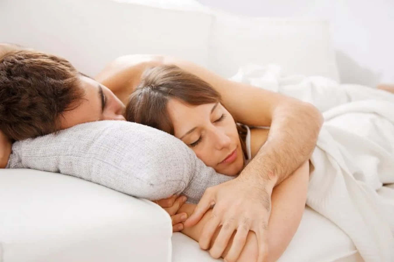 Sofa 桌布 壁紙 — 一對情侶在鋪著白色床單和枕頭的床上，在柔和的晨光中擁抱著安然入睡。