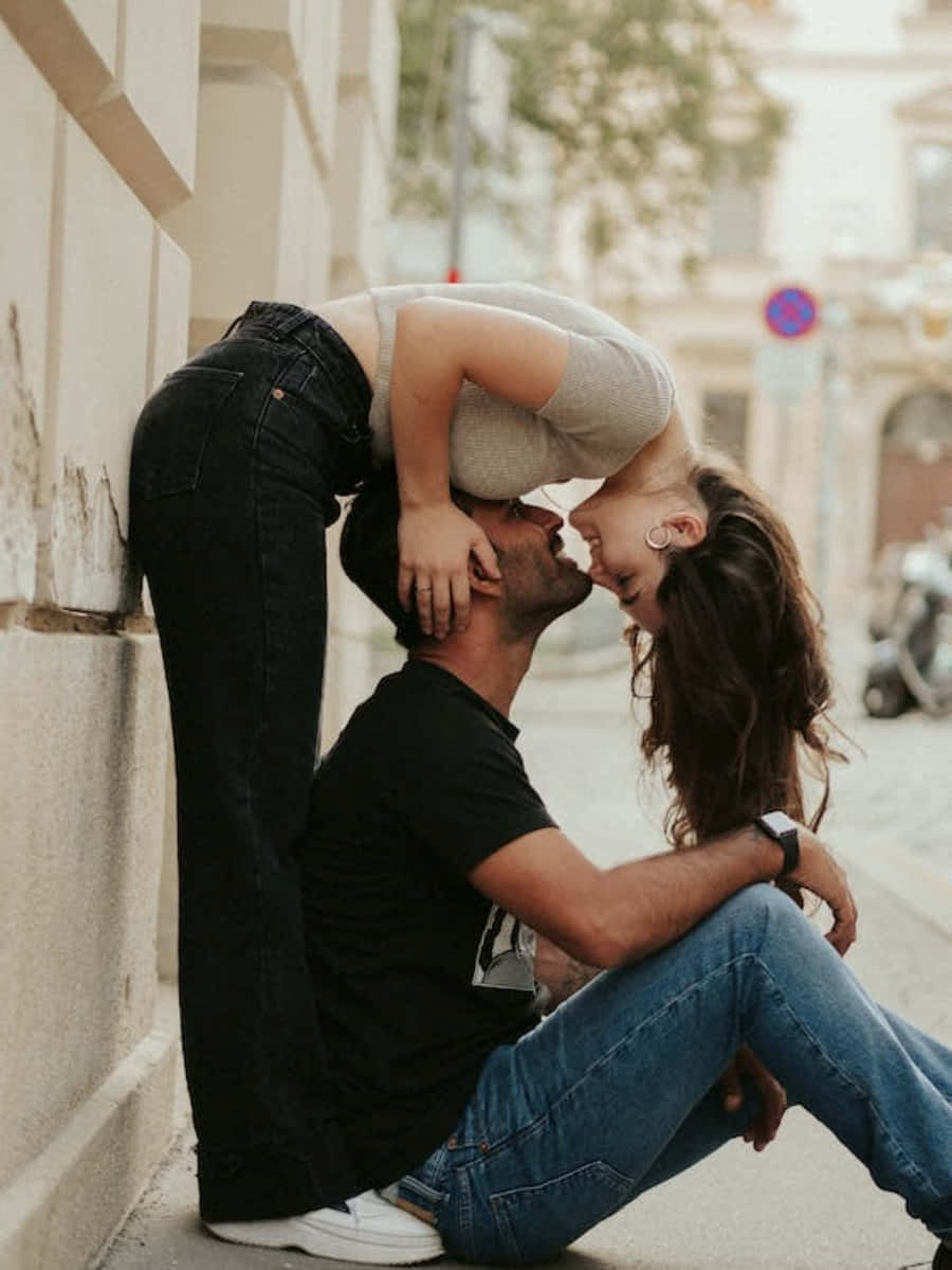 Boyfriend And Girlfriend 桌布 壁紙 — 一對情侶在陽光明媚的城市街道上以俏皮的姿勢親吻，背景色調溫暖，焦點柔和。