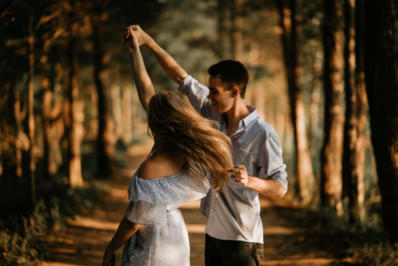 Romantic Love 桌布 壁紙 — 一對情侶在陽光明媚的森林中親密起舞，金色光線穿過高大的樹木。