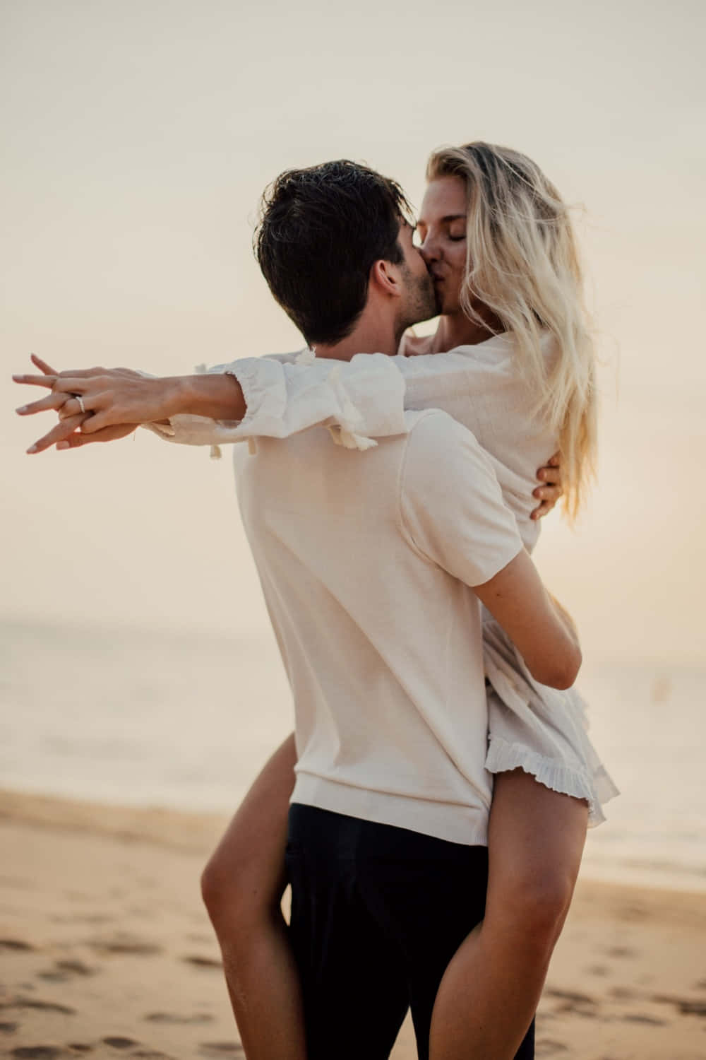 Kissing 桌布 壁紙 — 一對情侶在陽光明媚的海灘上熱情接吻，男子將女子抱在懷中。