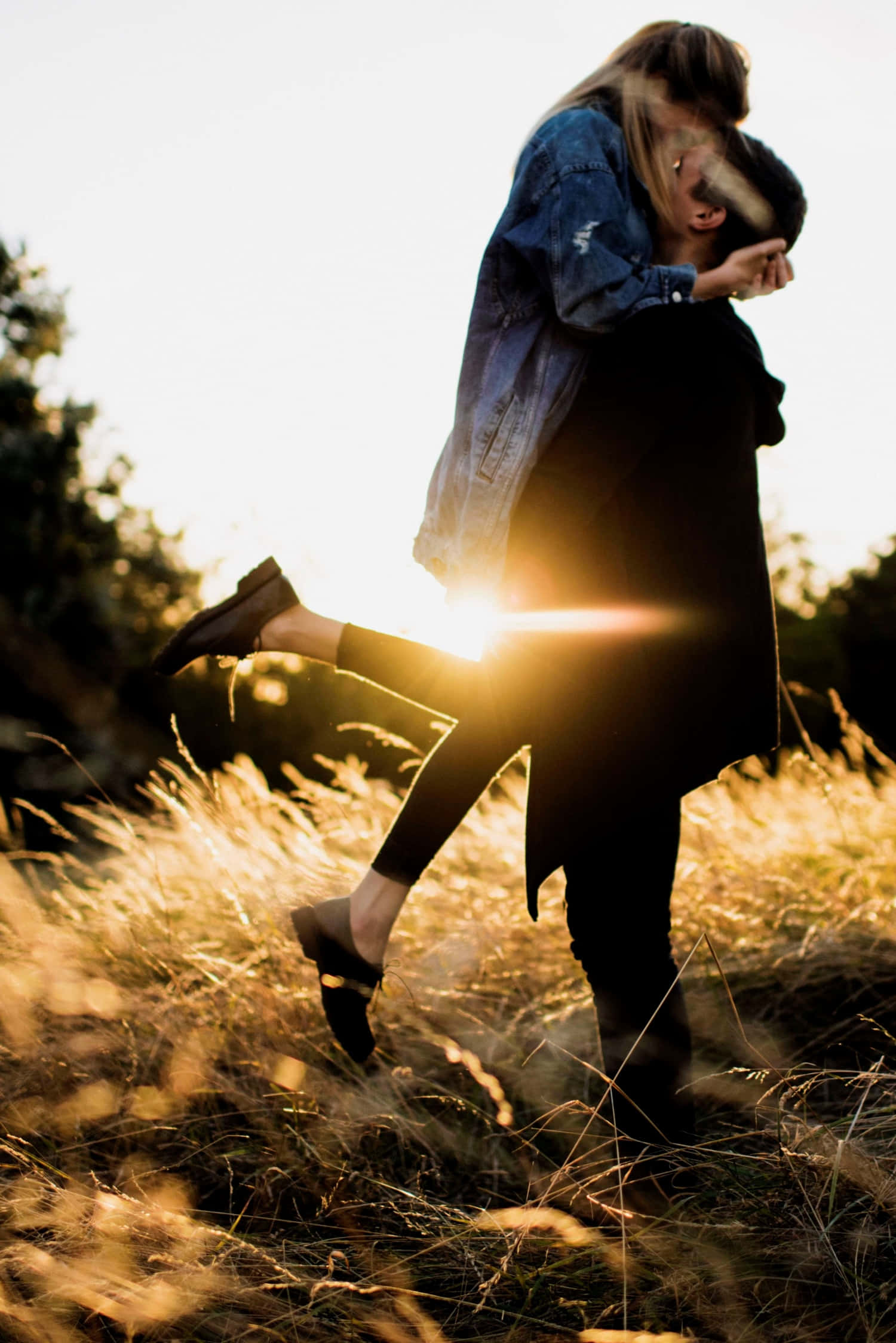 Boyfriend And Girlfriend 桌布 壁紙 — 一對情侶在陽光明媚的田野中熱情擁抱，金色光芒在他們身後閃耀。