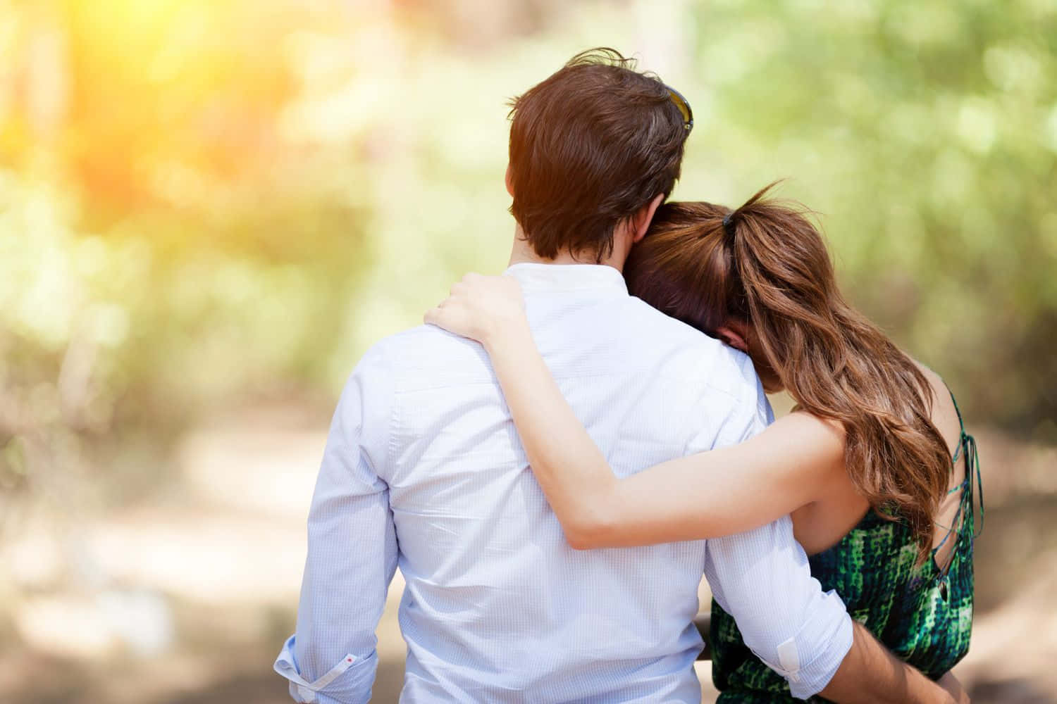 Romantic Love 桌布 壁紙 — 一對情侶在陽光普照的公園中從後擁抱，背景有柔和散景樹葉。
