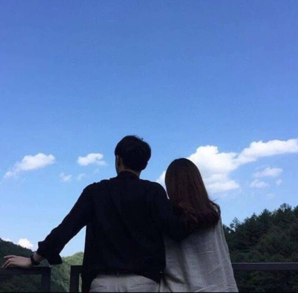 Relationship 桌布 壁紙 — 一對情侶在陽台上從後擁抱，俯瞰森林，廣闊藍天白雲點綴。