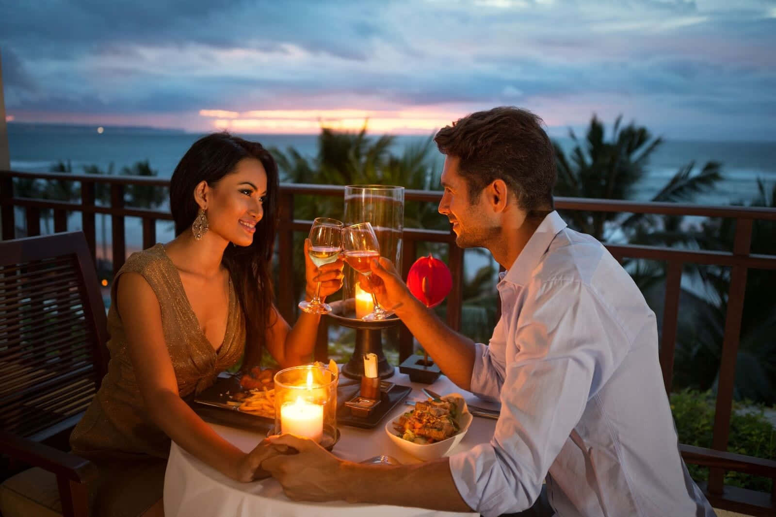 Beautiful Couple 桌布 壁紙 — 一對情侶在陽台上用酒杯敬酒，身後絢麗的夕陽描繪著海洋的天空。