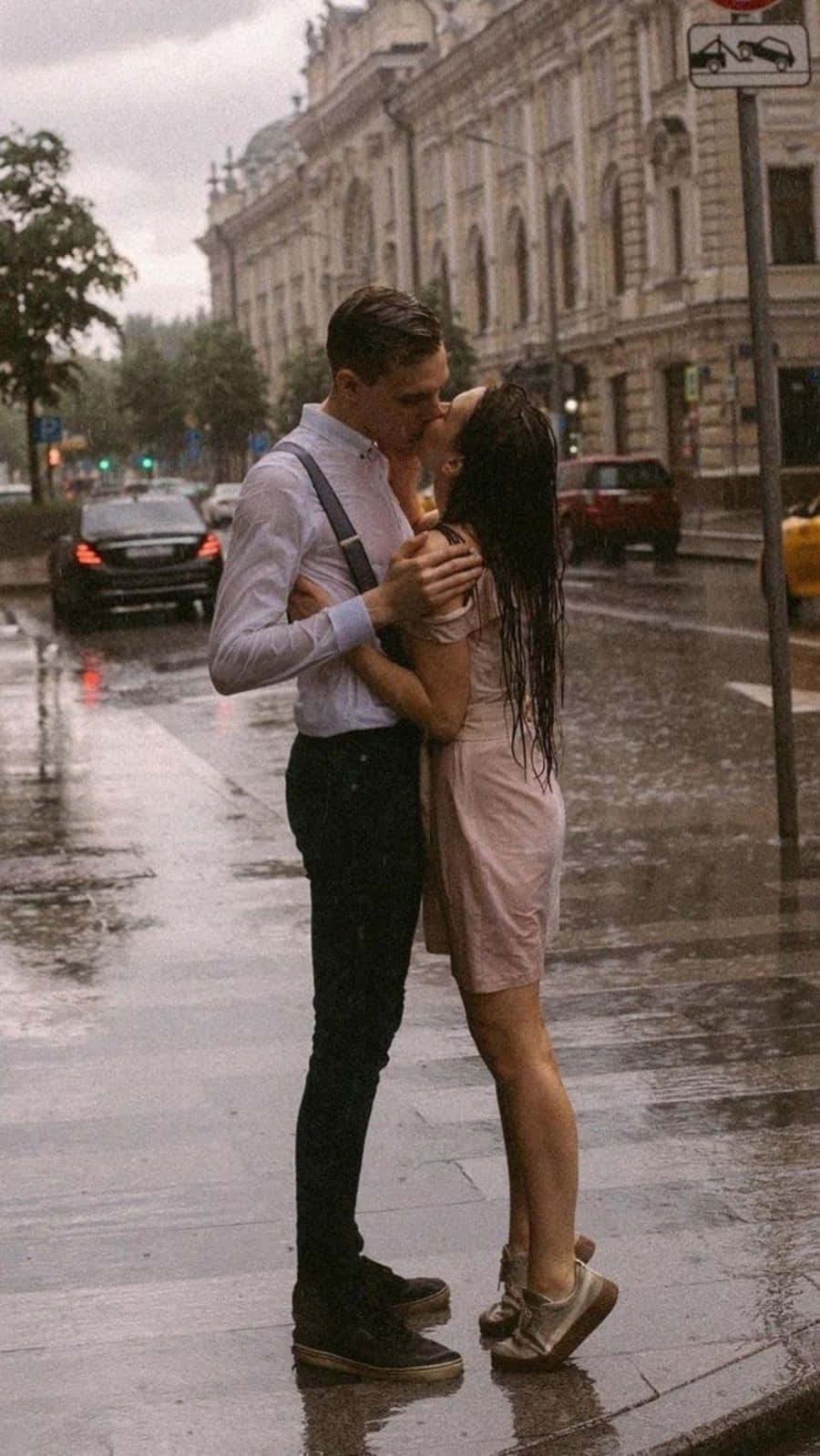Kissing 桌布 壁紙 — 一對情侶在雨中的城市街道上親密接吻，濕漉漉的人行道反射出路燈和復古建築的背景。