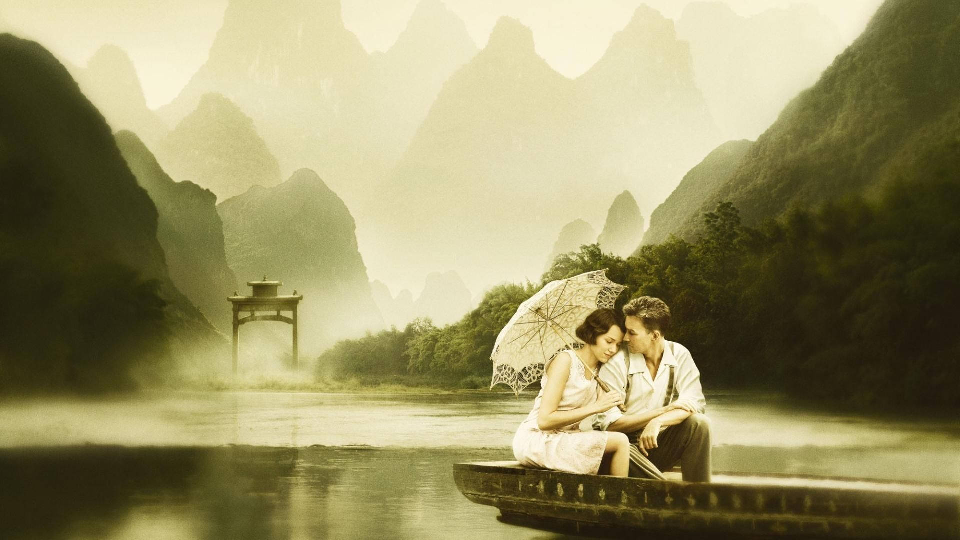 Love Story 桌布 壁紙 — 一對情侶在霧氣瀰漫的河上，在船中撐傘共享親密時刻，四周環繞著高聳的喀斯特山峰。