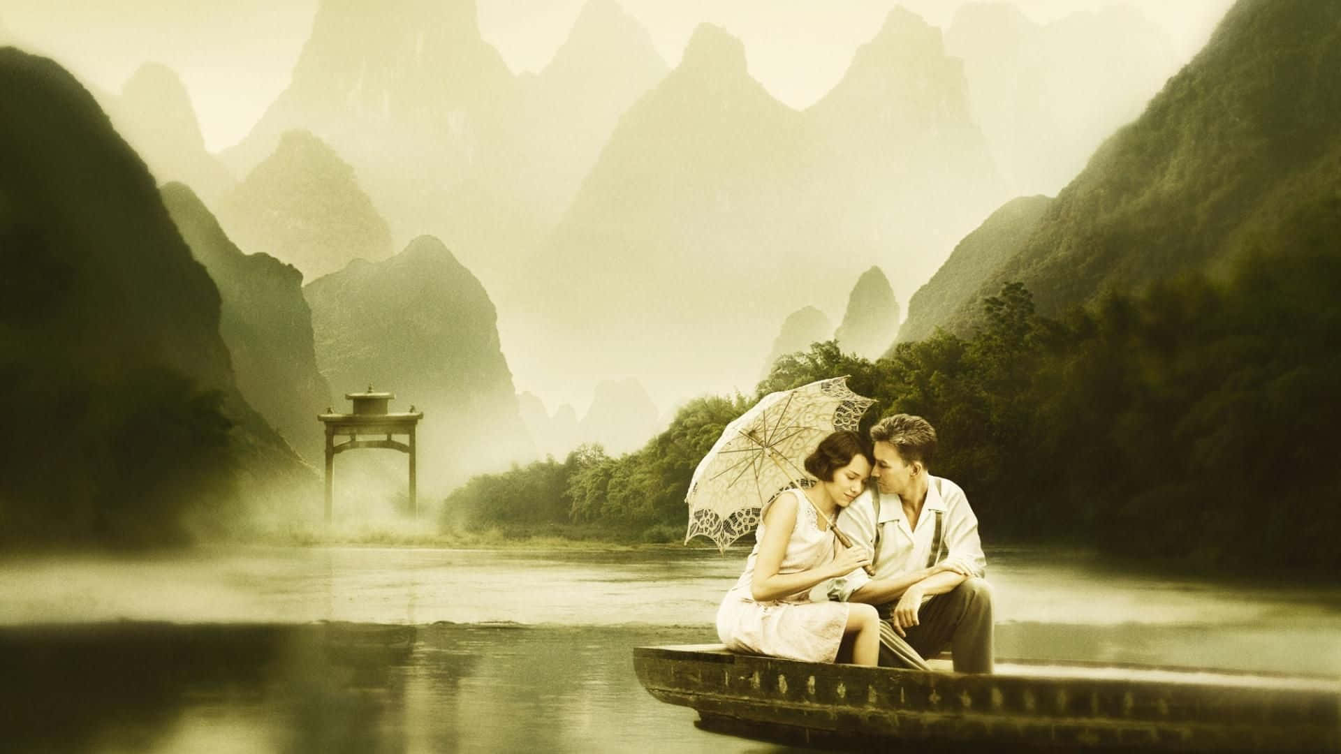 Romanticism 桌布 壁紙 — 一對情侶在霧氣瀰漫的河流上的小船中，在雨傘下分享親密時刻，周圍是高聳的喀斯特山脈。
