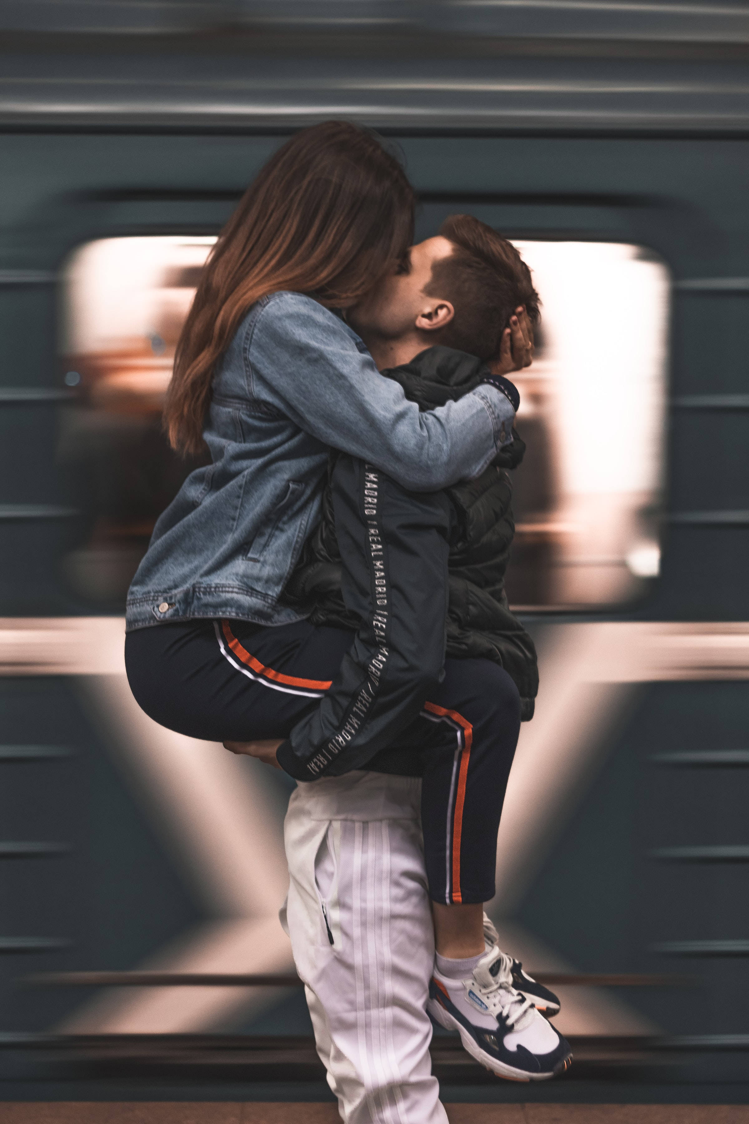Couple 桌布 壁紙 — 一對情侶在高速行駛的火車前熱情接吻，男子將女子抱起，背景呈現動態模糊效果。
