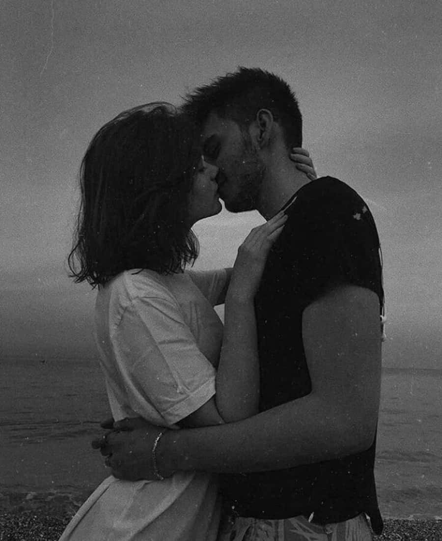 Kissing 桌布 壁紙 — 一對情侶在黃昏時分霧氣瀰漫的海灘上激情接吻的黑白照片。