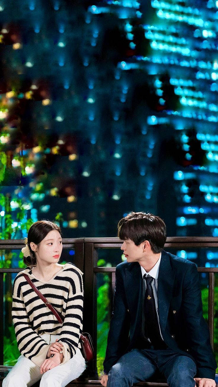 Couples 桌布 壁紙 — 一對情侶晚上坐在陽台上，在閃爍的城市天際背景下凝視彼此的眼睛。
