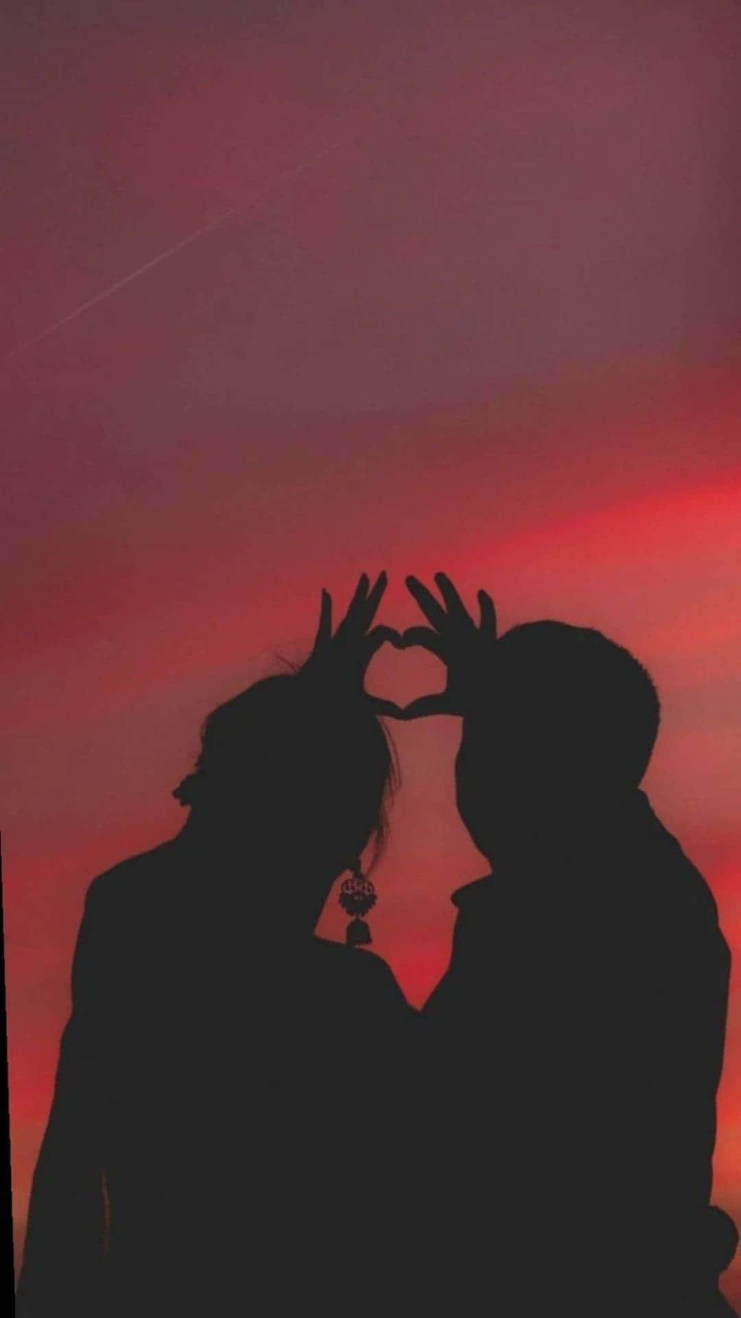 Silhouette 桌布 壁紙 — 一對情侶的剪影，雙手比心，背景是火紅的日落天空。