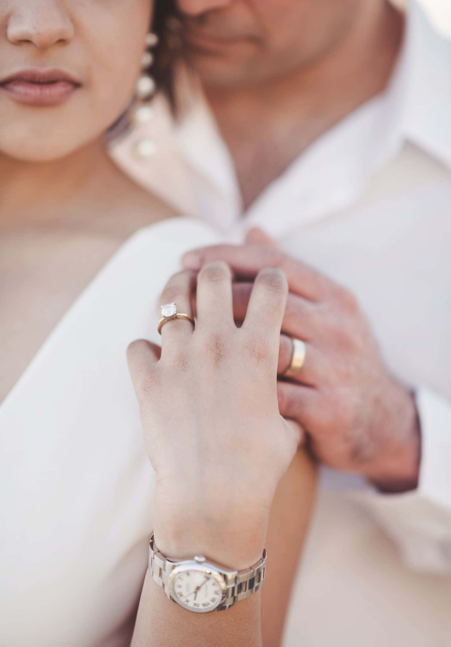 engagement 桌布 壁紙 — 一對情侶的手緊握在一起，戴著結婚戒指和手錶，背景是柔軟的白色衣物。
