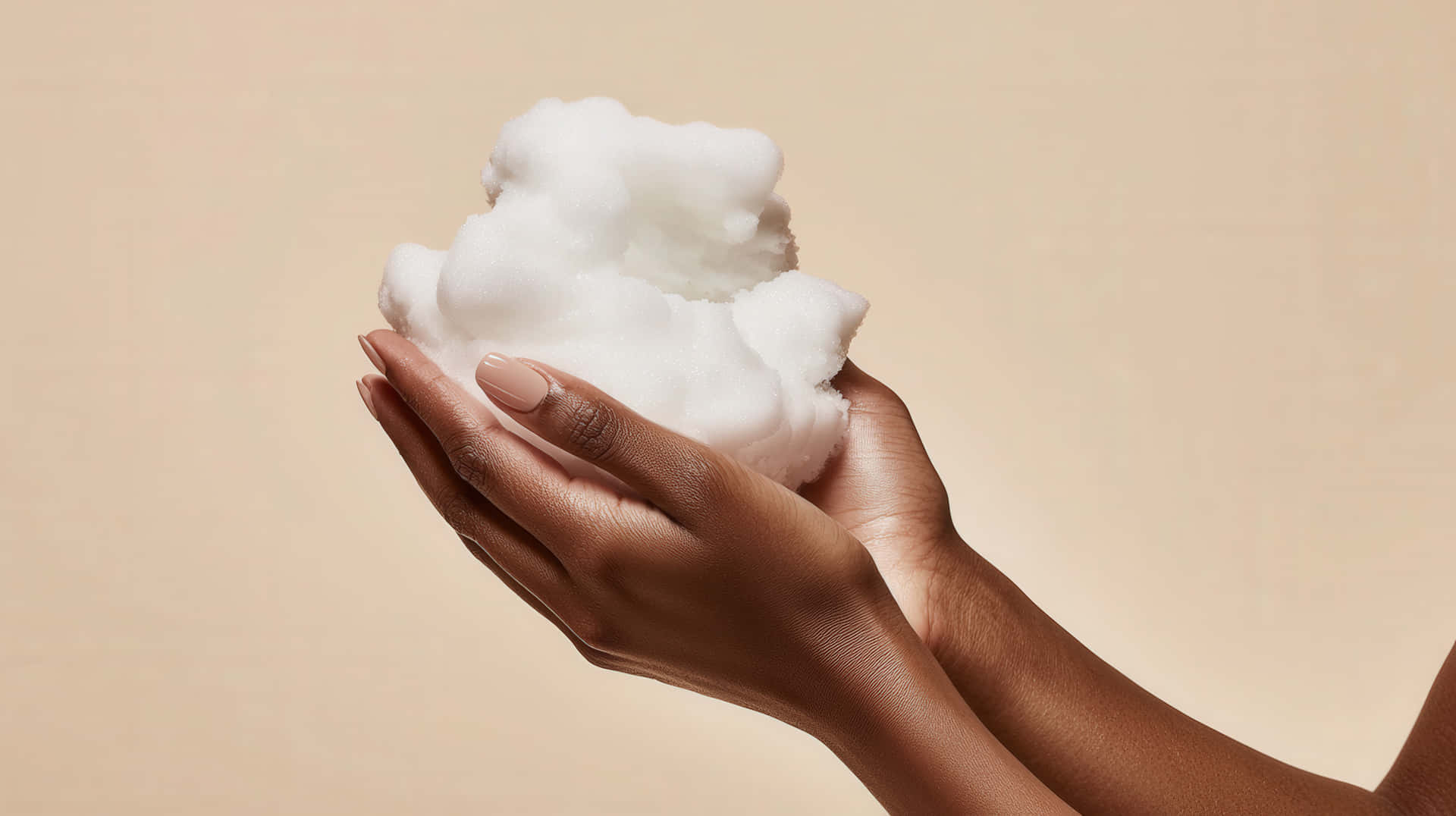Hands Holding Soft White Foam on a Neutral Background for Skincare and Beauty Concept 壁紙 — 一對手捧著一個柔軟蓬鬆的白色雲朵，背景是溫暖的米色。