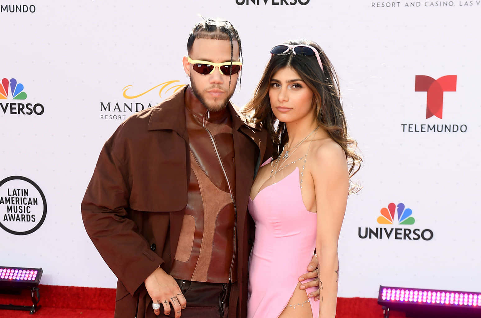 Mia Khalifa 桌布 壁紙 — 一對時尚情侶在拉丁美洲音樂獎的紅地毯上，在品牌背景和閃爍燈光下擺姿勢。