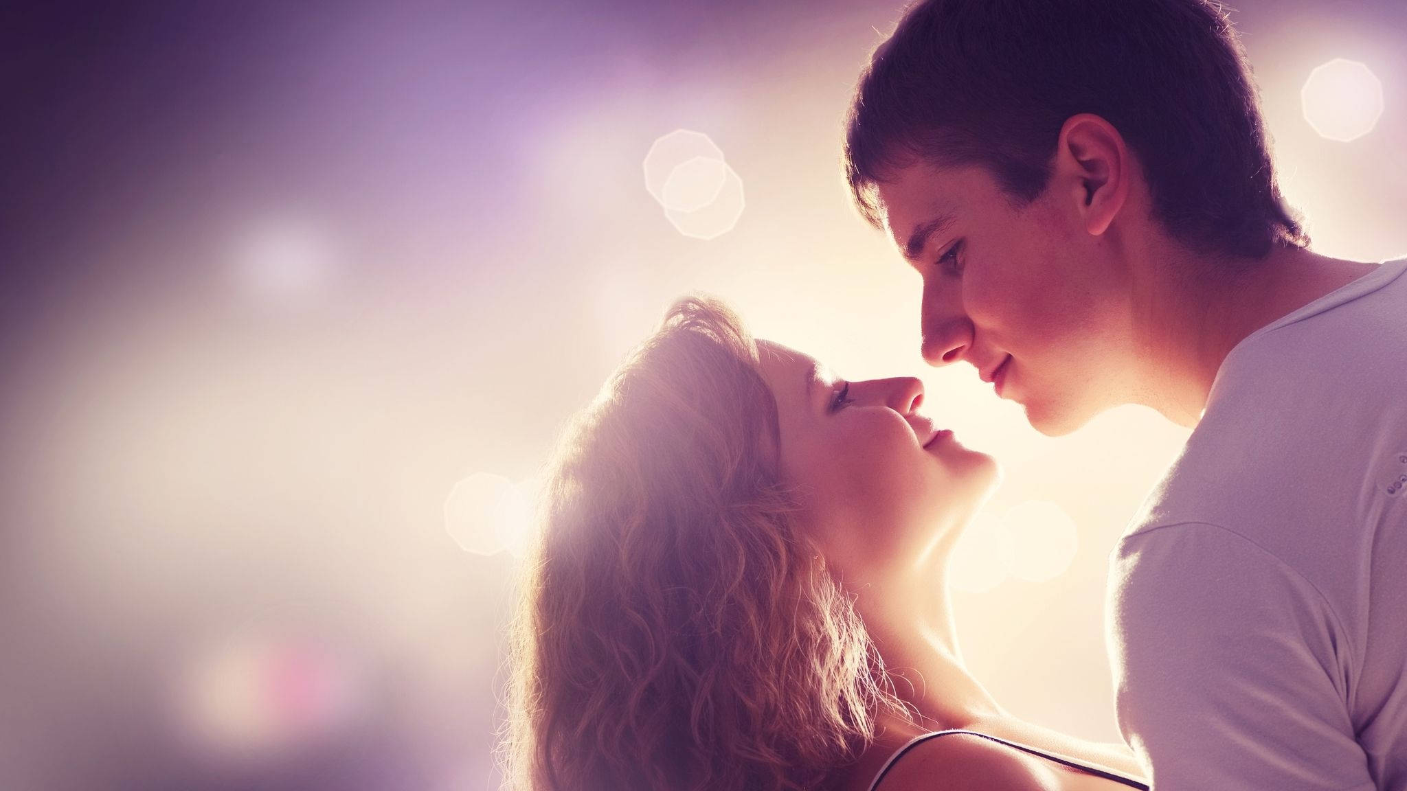 Couples 桌布 壁紙 — 一對浪漫情侶在溫暖的金色光芒中凝視彼此的眼睛，背景是柔和發光的散景。