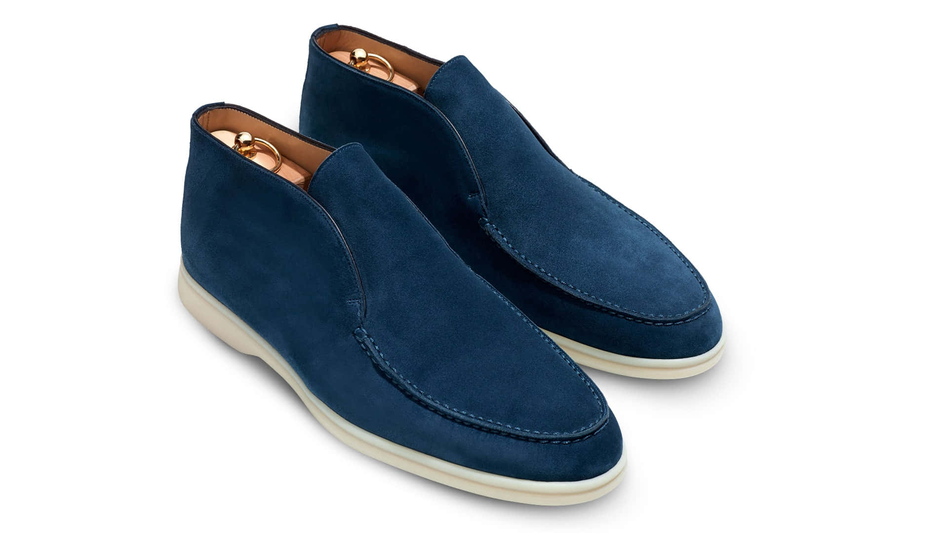 Mens Fashion 桌布 壁紙 — 一對海軍藍色麂皮懶人鞋，搭配奶油色鞋底和金色鞋眼，展示在潔白背景上。