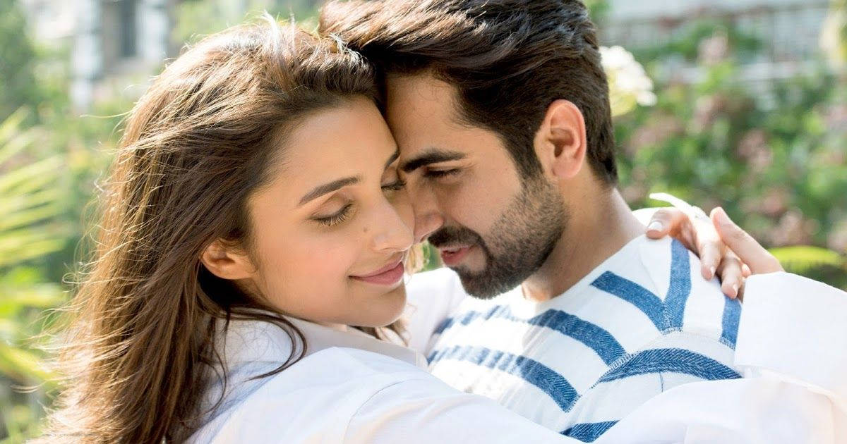 ayushmann khurrana 桌布 壁紙 — 一對溫柔的情侶在戶外擁抱，陽光透過他們身後翠綠的樹葉灑落下來。
