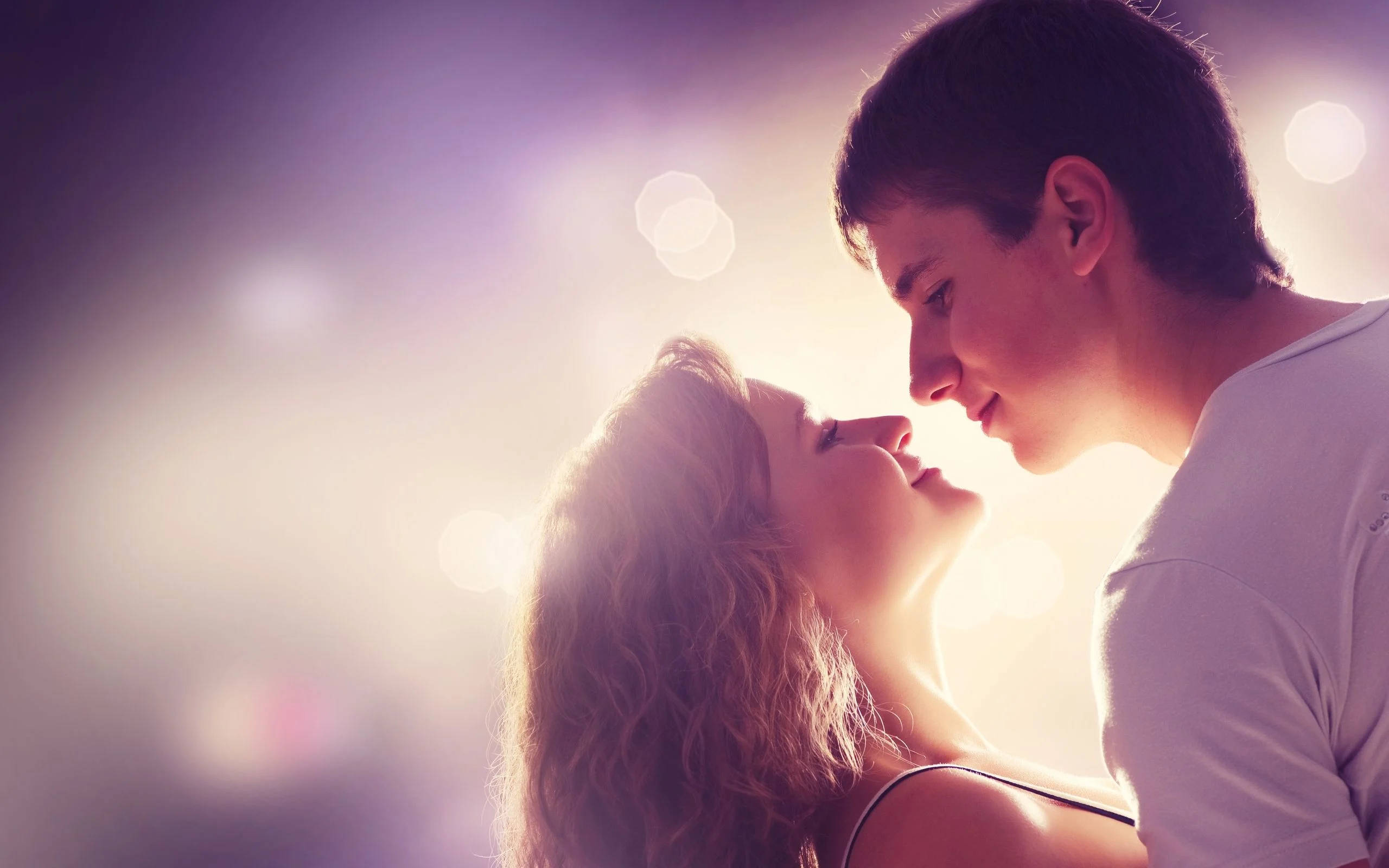 Romantic Love 桌布 壁紙 — 一對溫柔的情侶在溫暖的金色背光與柔和發光散景中分享親密時刻。
