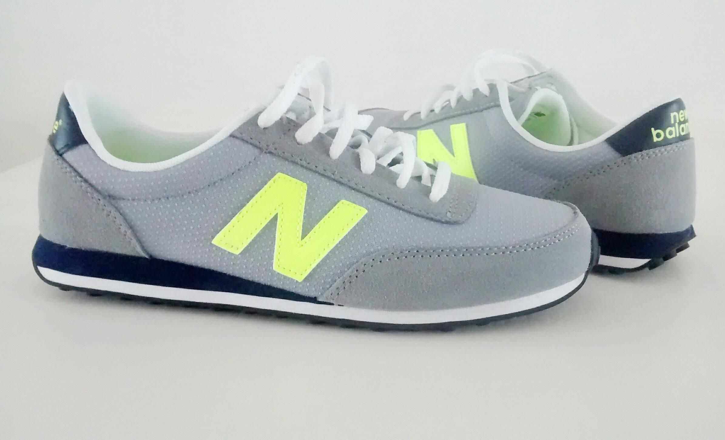 New 桌布 壁紙 — 一對灰色New Balance運動鞋，帶有螢光黃色N標誌和白色鞋帶，放在純白色背景上。