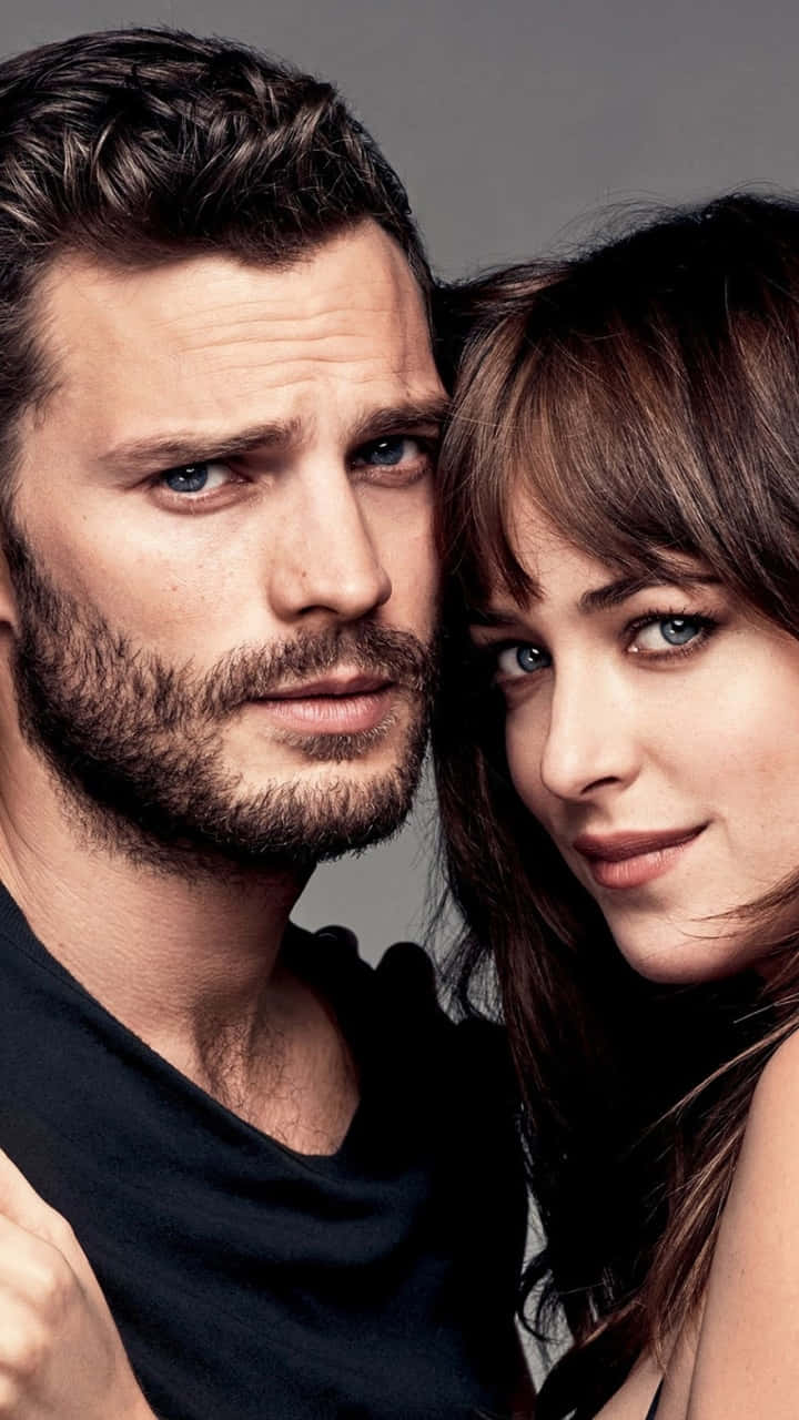jamie dornan 桌布 壁紙 — 一對男女的 close-up 肖像，擁有強烈的藍色眼睛，直視鏡頭，背景為中性灰色。
