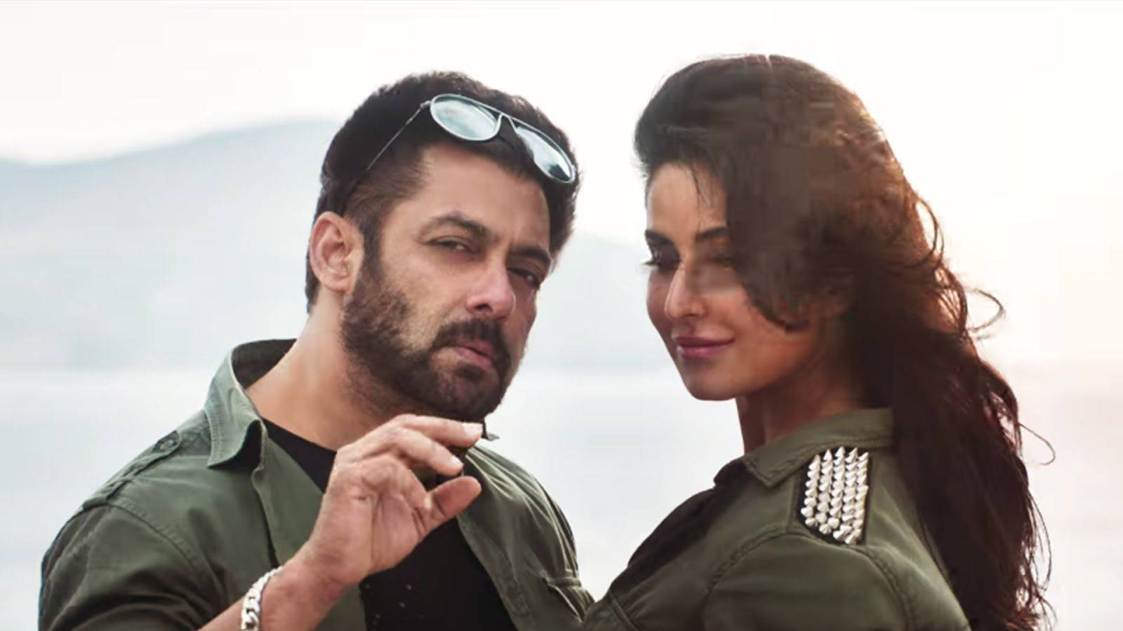 salman khan HD 桌布 壁紙 — 一對男女穿著相配的綠色外套，在朦朧的山景背景下互相凝視。