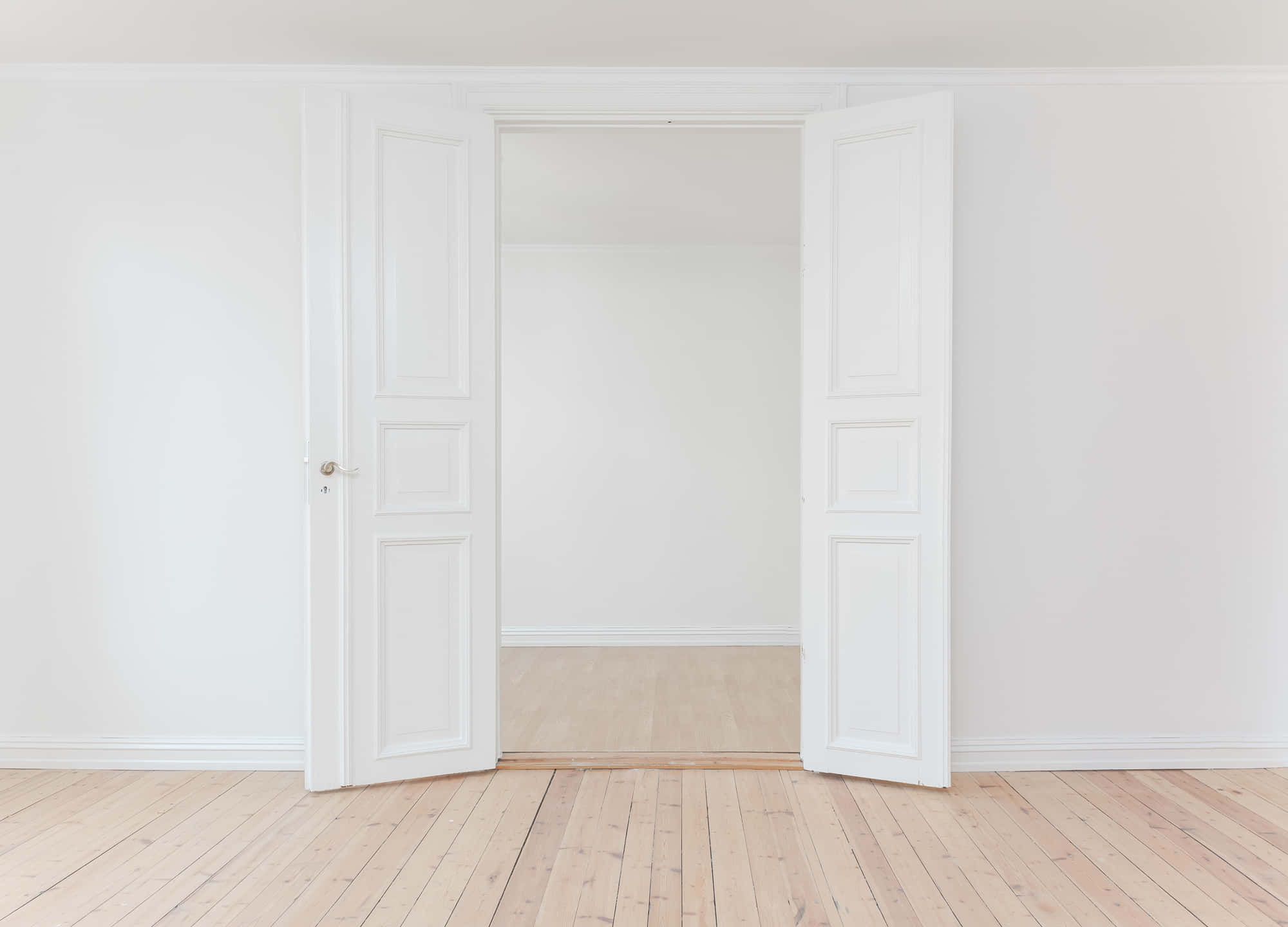 Empty Room 桌布 壁紙 — 一對白色鑲板門在一個極簡主義的房間中敞開，房間鋪有淺色木地板和白色牆壁。
