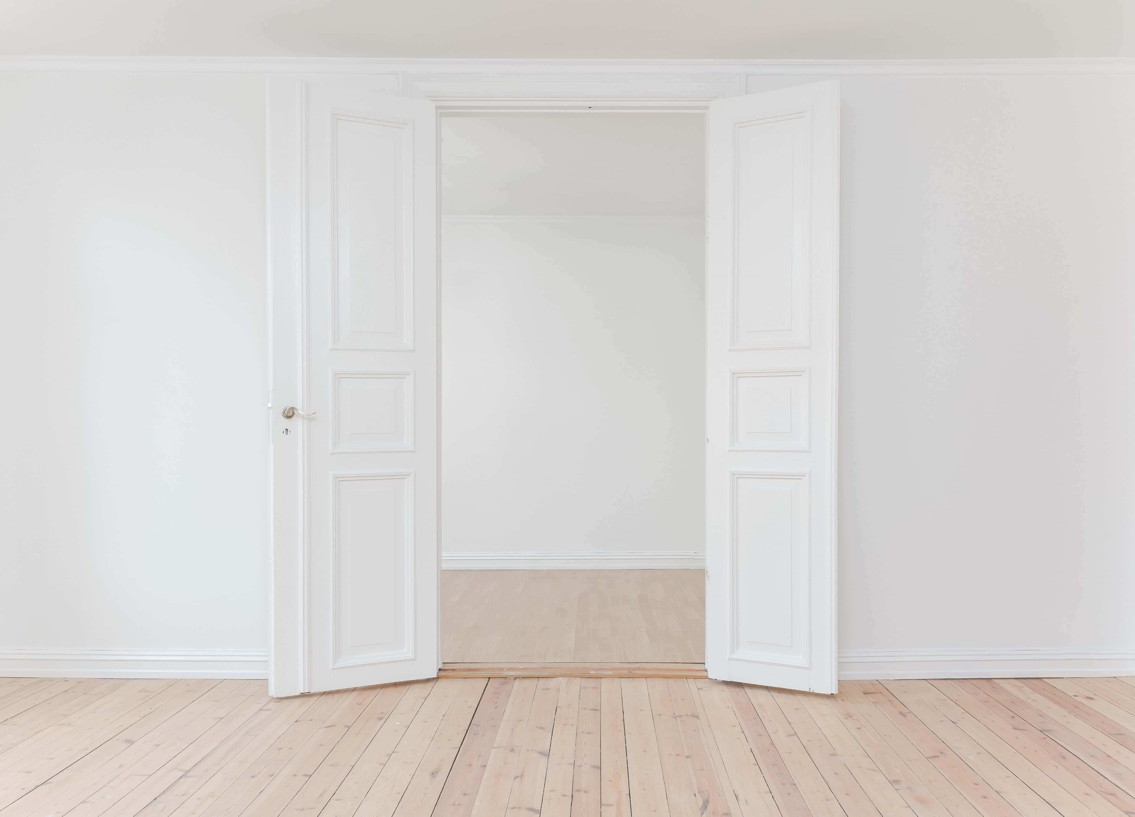 Empty Room 桌布 壁紙 — 一對白色鑲板門在一個簡約風格的房間中敞開，房間有淺色木地板和白色牆壁。