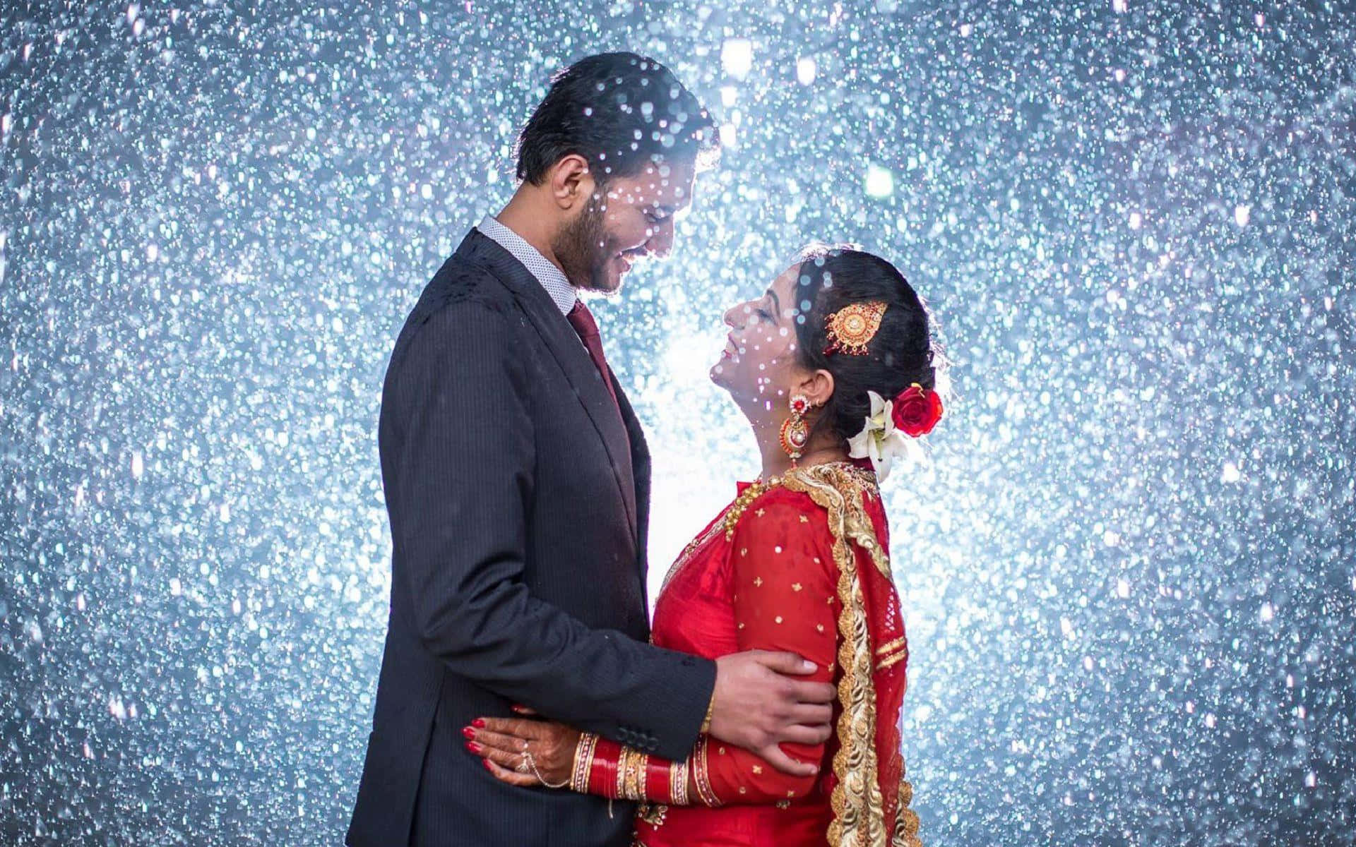  壁紙 — 一對穿著傳統婚禮服飾的情侶在閃爍的藍色背景和飄落的亮片中溫柔擁抱。