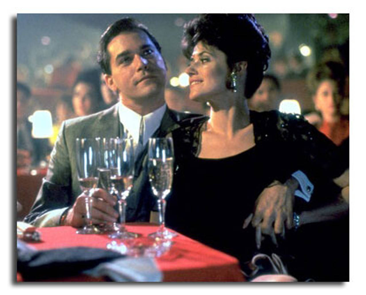 goodfellas 桌布 壁紙 — 一對穿著正裝的男女在燈光昏暗的餐廳裡，紅色桌布上放著香檳杯，分享親密時刻。