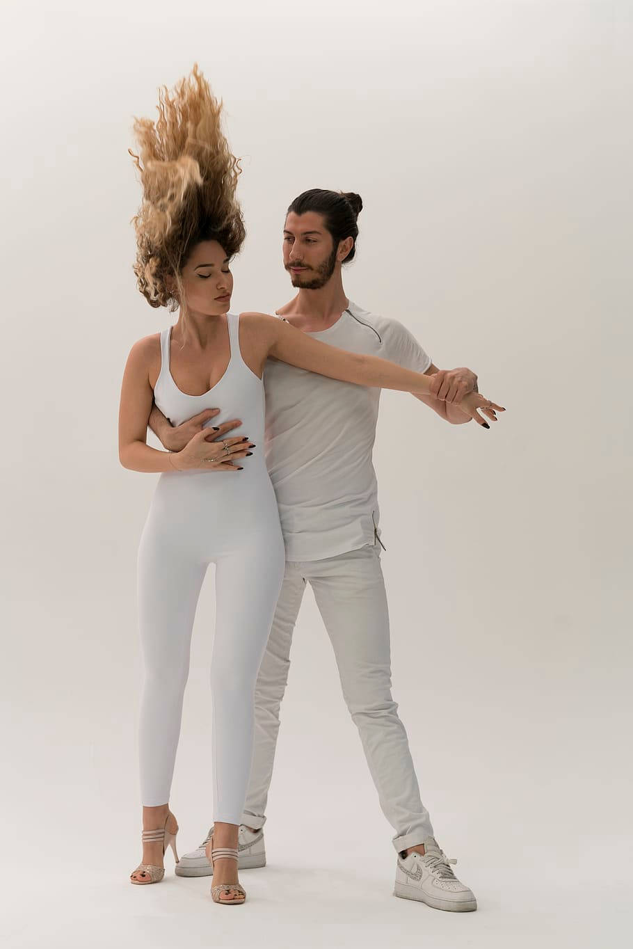 dancer 桌布 壁紙 — 一對穿著白色服裝的情侶擺姿勢，女士的頭髮戲劇性地對抗重力，背景是純白色。