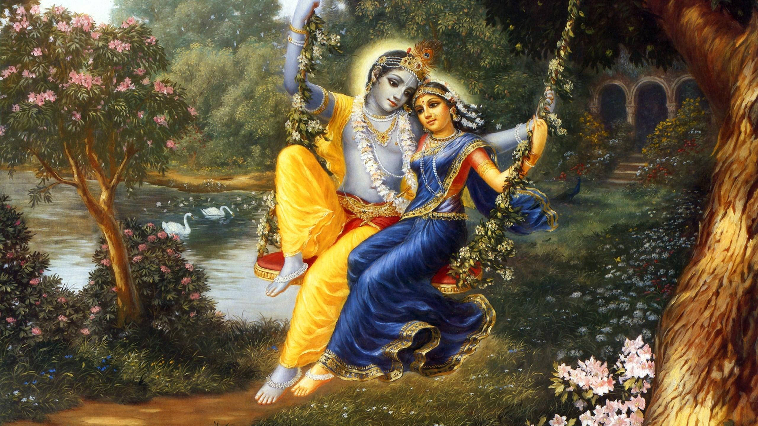 krishna god 桌布 壁紙 — 一對穿著華麗服飾的神聖情侶在一個佈滿花卉的鞦韆上分享親密時刻，周圍是茂密的花園，有天鵝和拱形建築。